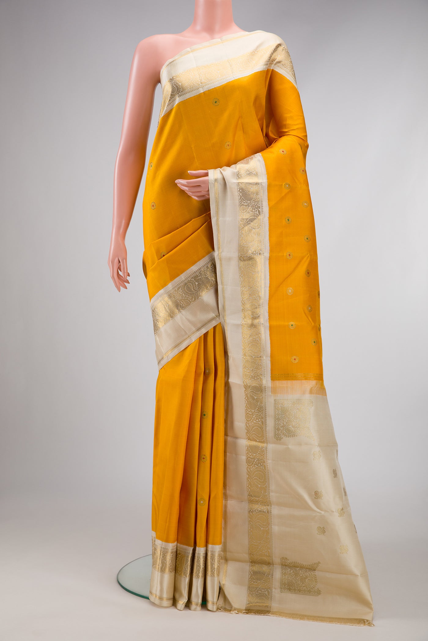 Pure Silk Pure Zari Mustard Dual Tone Kanjivaram Saree with Zari And Thread Butta on the body and Zari Border.  displayed on a mannequin