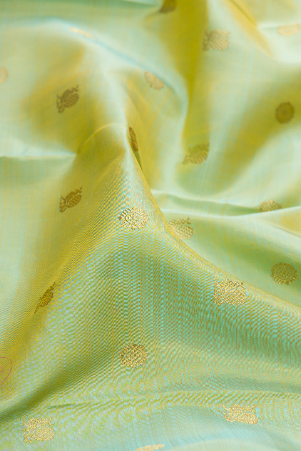 Close up of Pure Silk Pure Zari Pista Green Kanjivaram Saree with Zari Butta on the body and Zari Border.  displaying folds