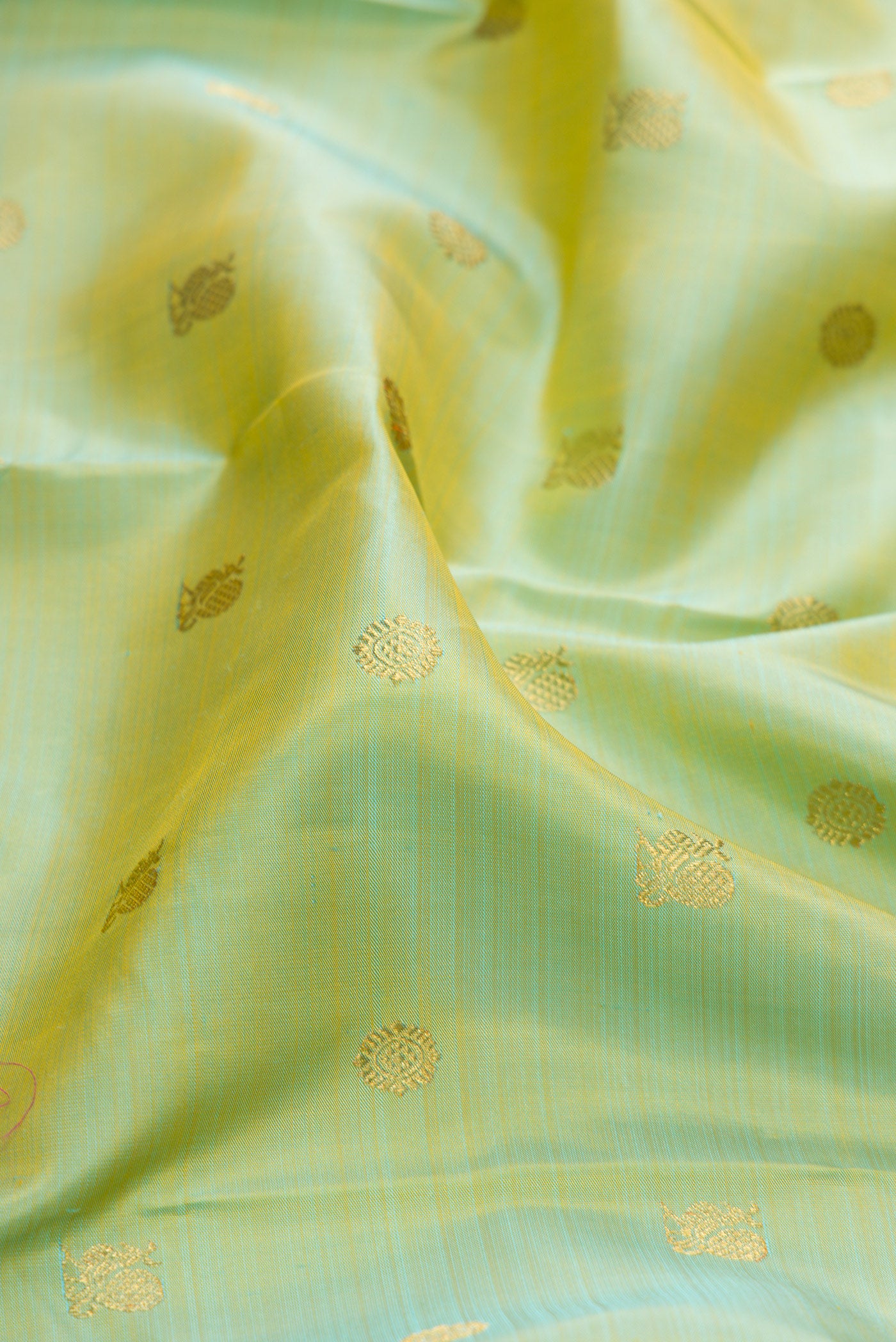 Close up of Pure Silk Pure Zari Pista Green Kanjivaram Saree with Zari Butta on the body and Zari Border.  displaying folds