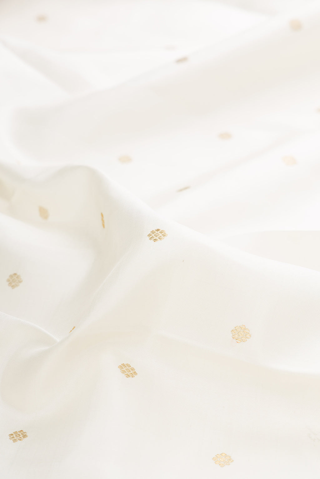 Close up of Pure Silk Pure Zari Off White Kanjivaram Saree with Zari Butta on the body and Zari Border.  displaying folds