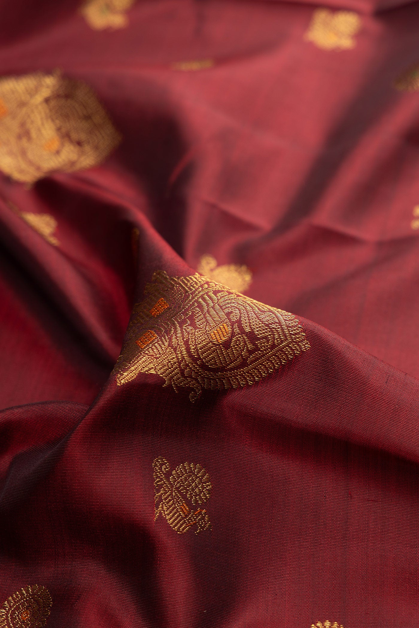 Close up of Pure Silk Pure Zari Maroon Kanjivaram Saree with Zari Butta on the body and Zari Border.  displaying folds