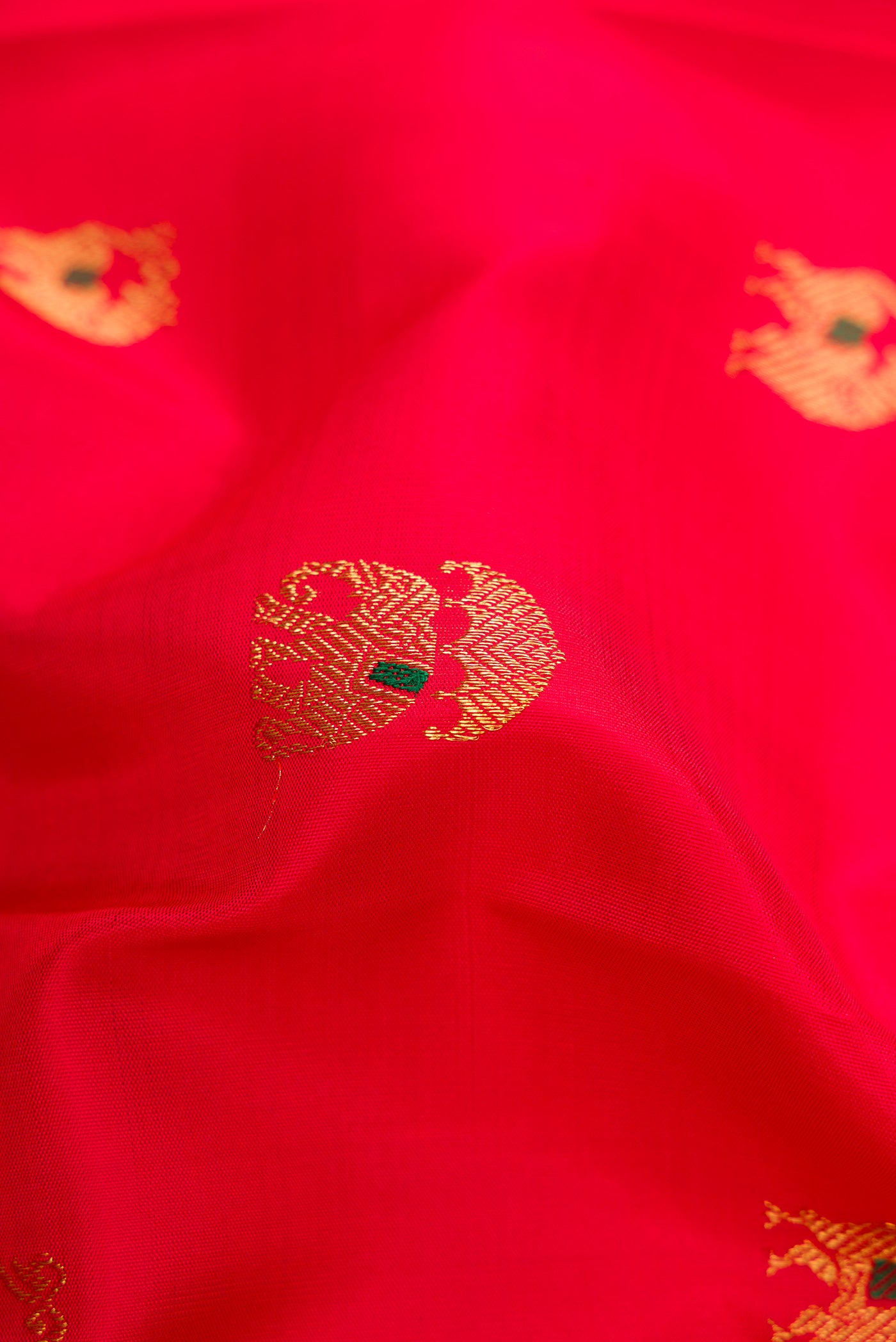 Close up of Pure Silk Pure Zari Red Dual Tone Kanjivaram Saree with Zari And Thread Butta on the body and Zari Border.  displaying folds