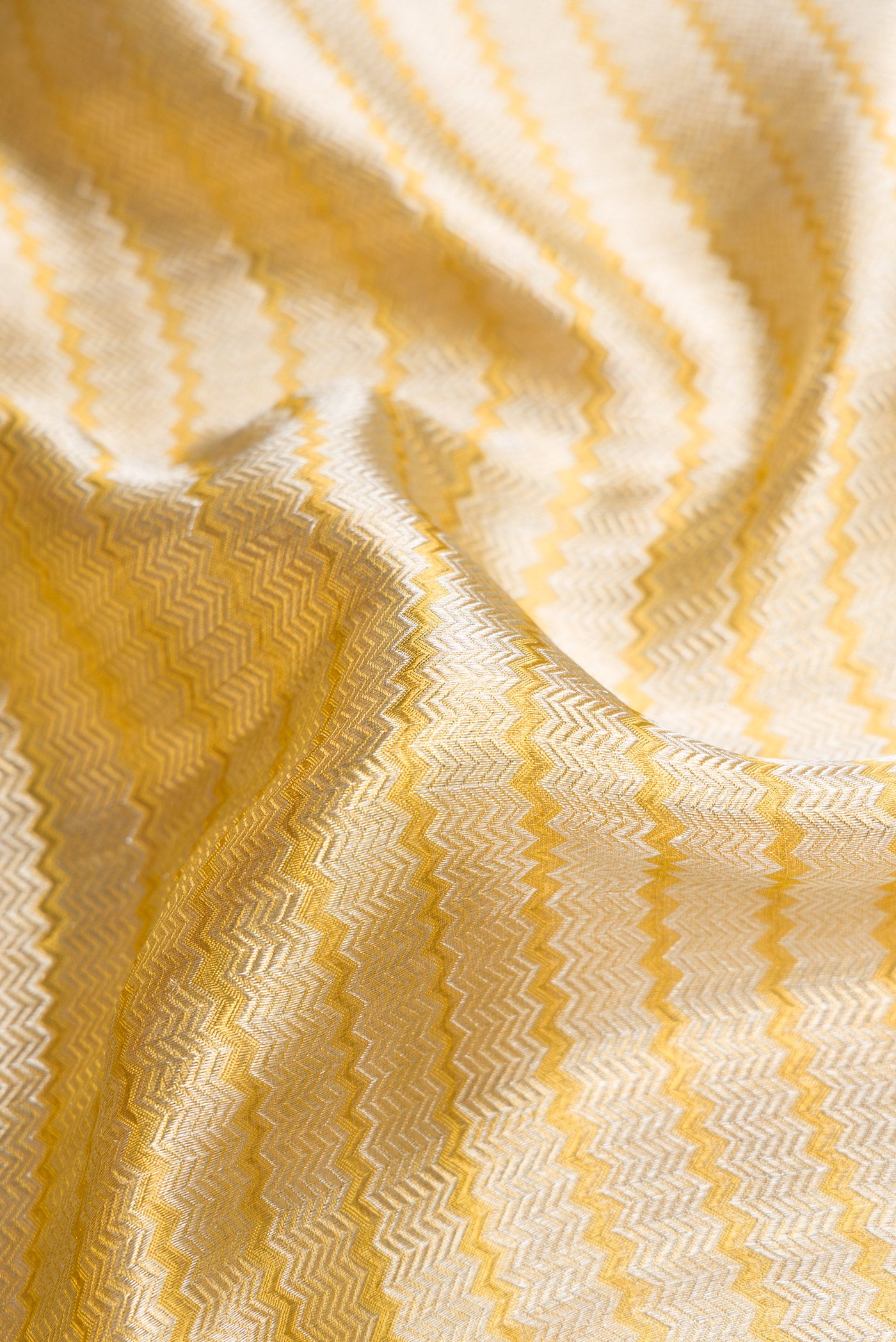 Close up of Silver Dual Tone Kanjivaram Tissue Silk Saree with Zari Brocade on the body and Zari Border.  displaying folds