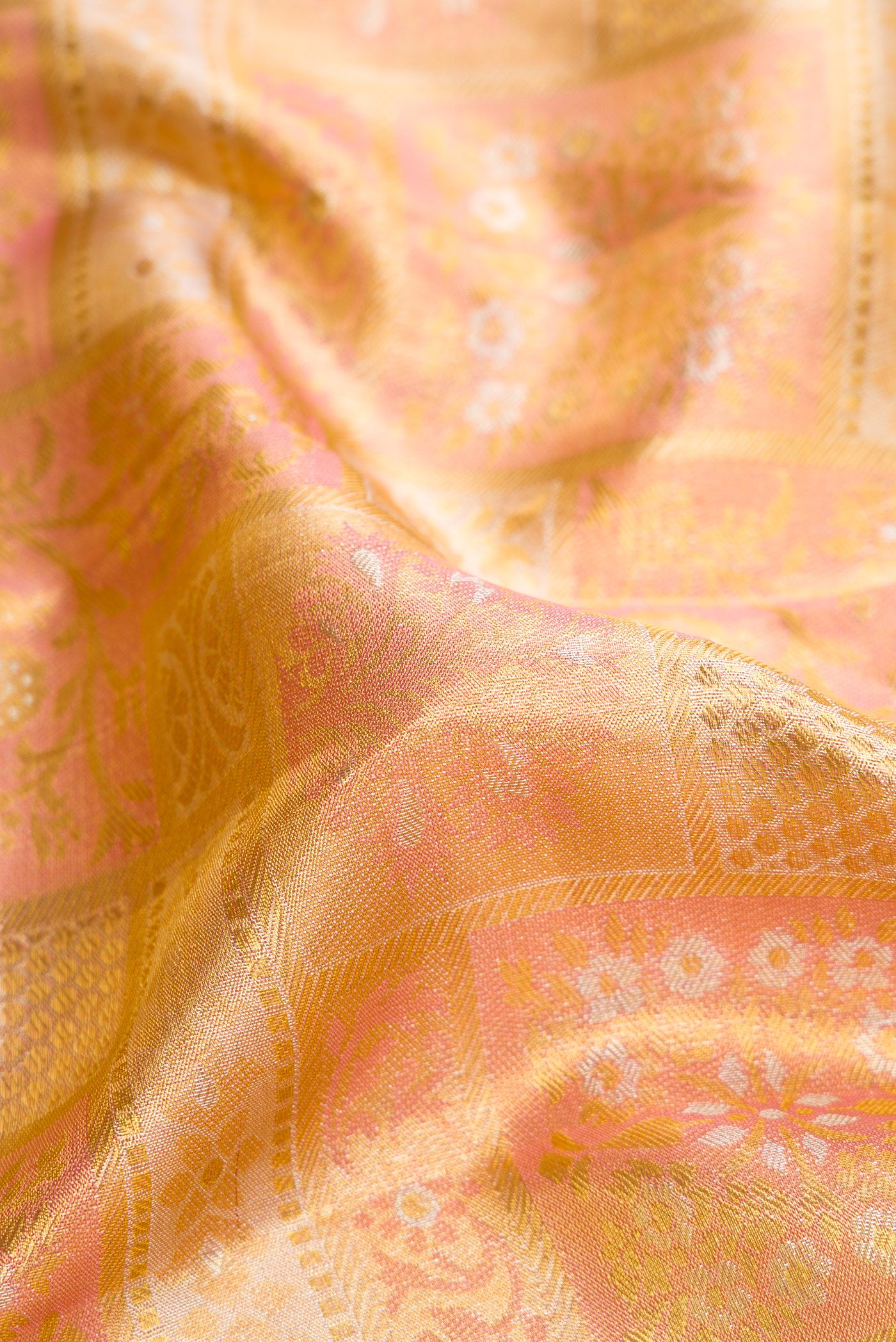 Close up of Rose Gold Dual Tone Kanjivaram Tissue Silk Saree with Zari Brocade on the body and Zari Border.  displaying folds