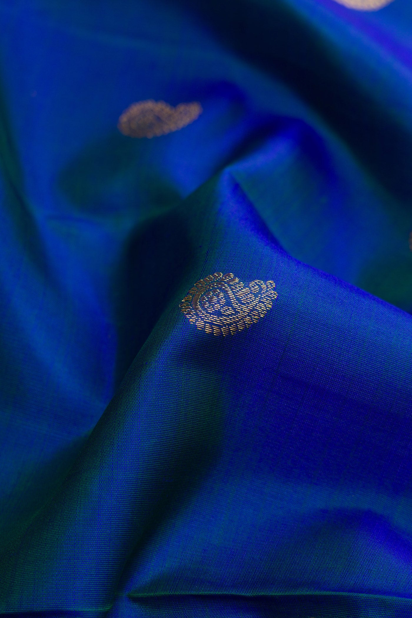 Close up of Pure Silk Pure Zari Peacock Blue Dual Tone Kanjivaram Saree with Zari Butta on the body and Zari Border.  displaying folds