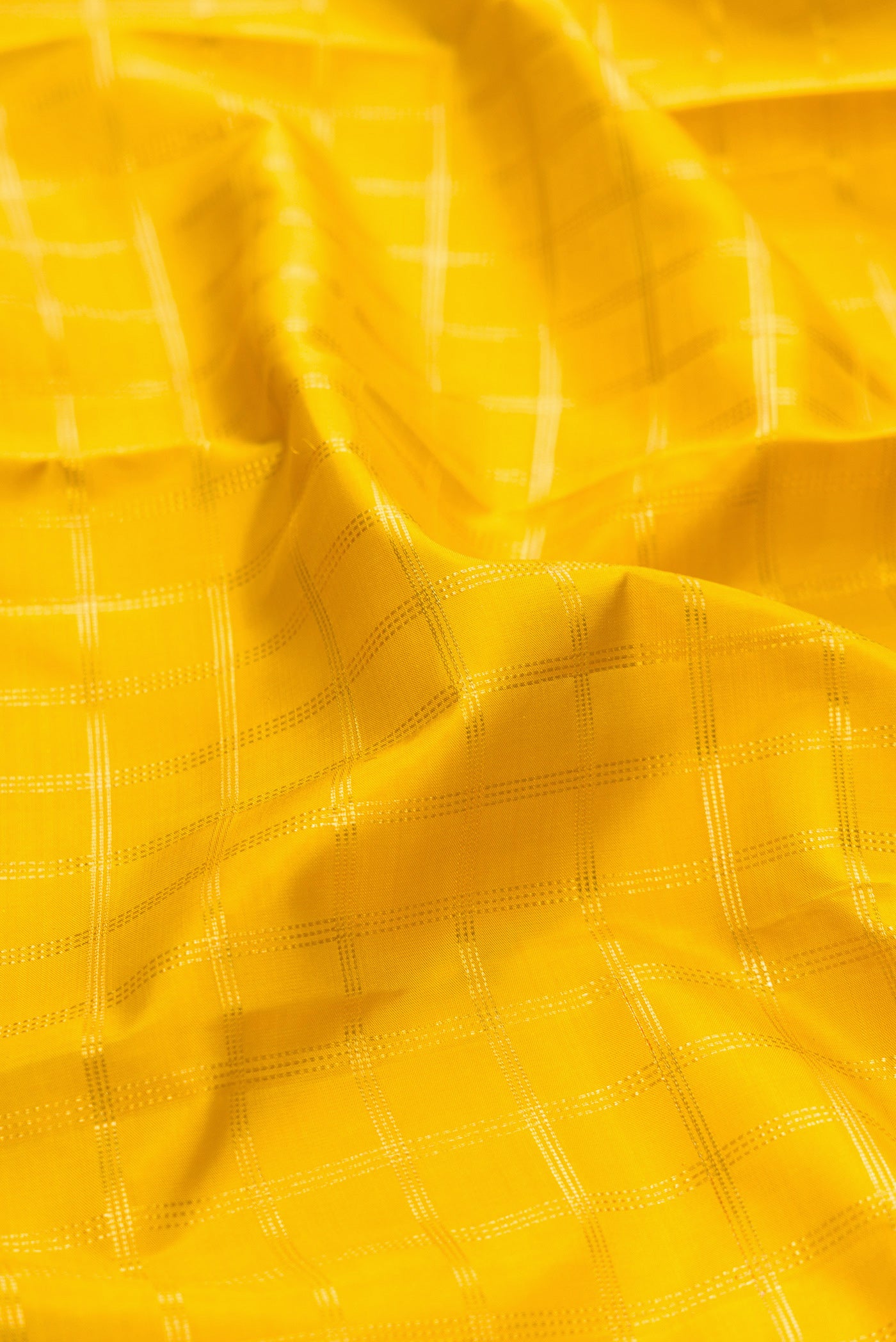 Close up of Yellow Kanjivaram Silk Saree with Checked design on the body and Fancy Border.  displaying folds