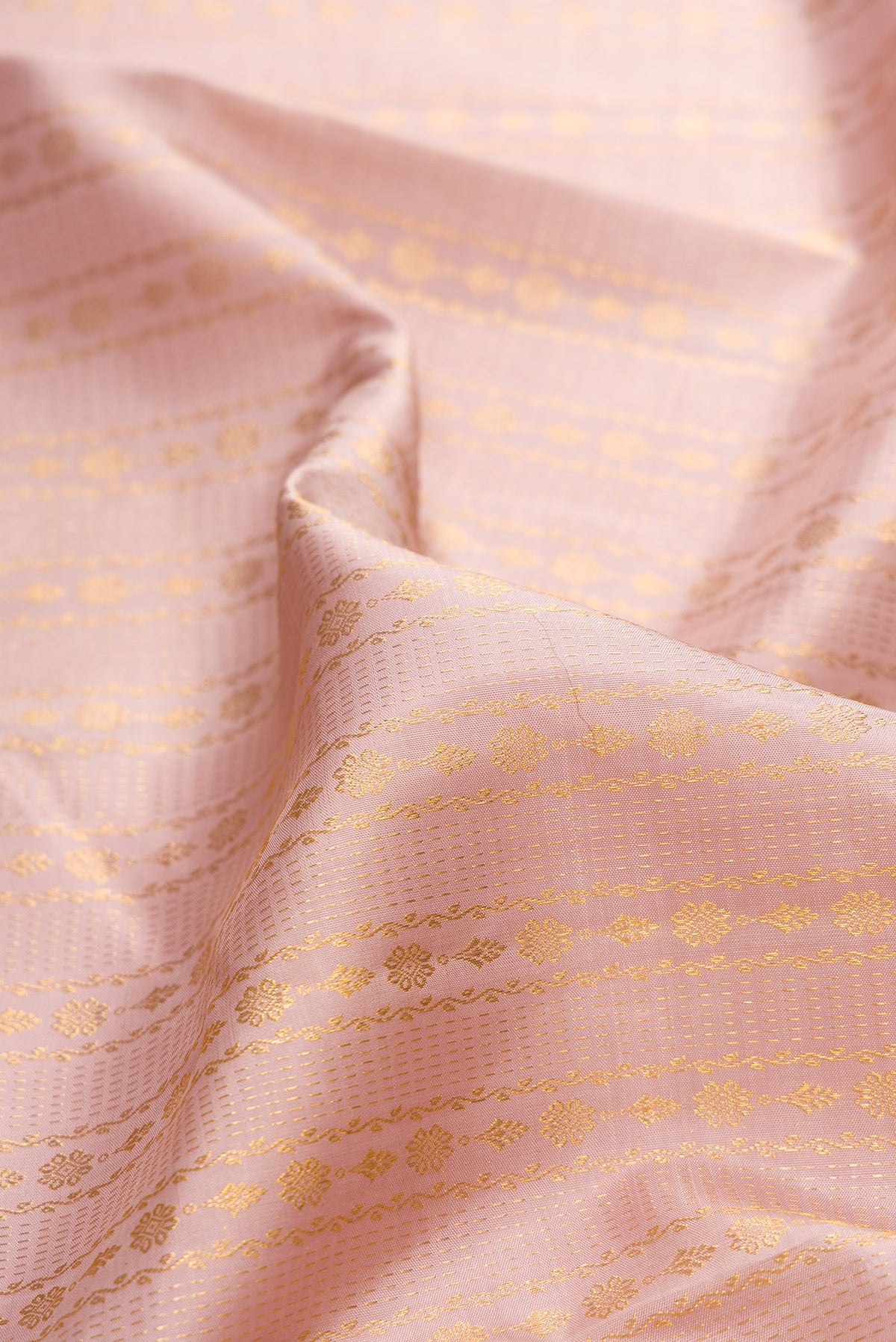 Close up of Pure Silk Rose Gold Kanchipuram Saree with Zari Brocade on the body and Zari Border.  displaying folds