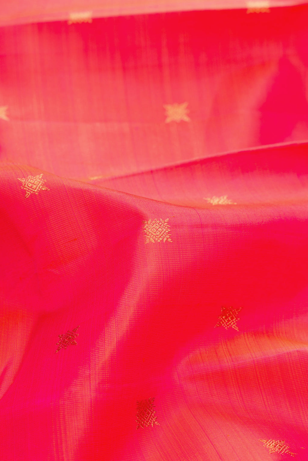 Close up of Pure Silk Pure Zari Coral Dual Tone Kanchipuram Saree with Zari Butta on the body and Zari Border.  displaying folds