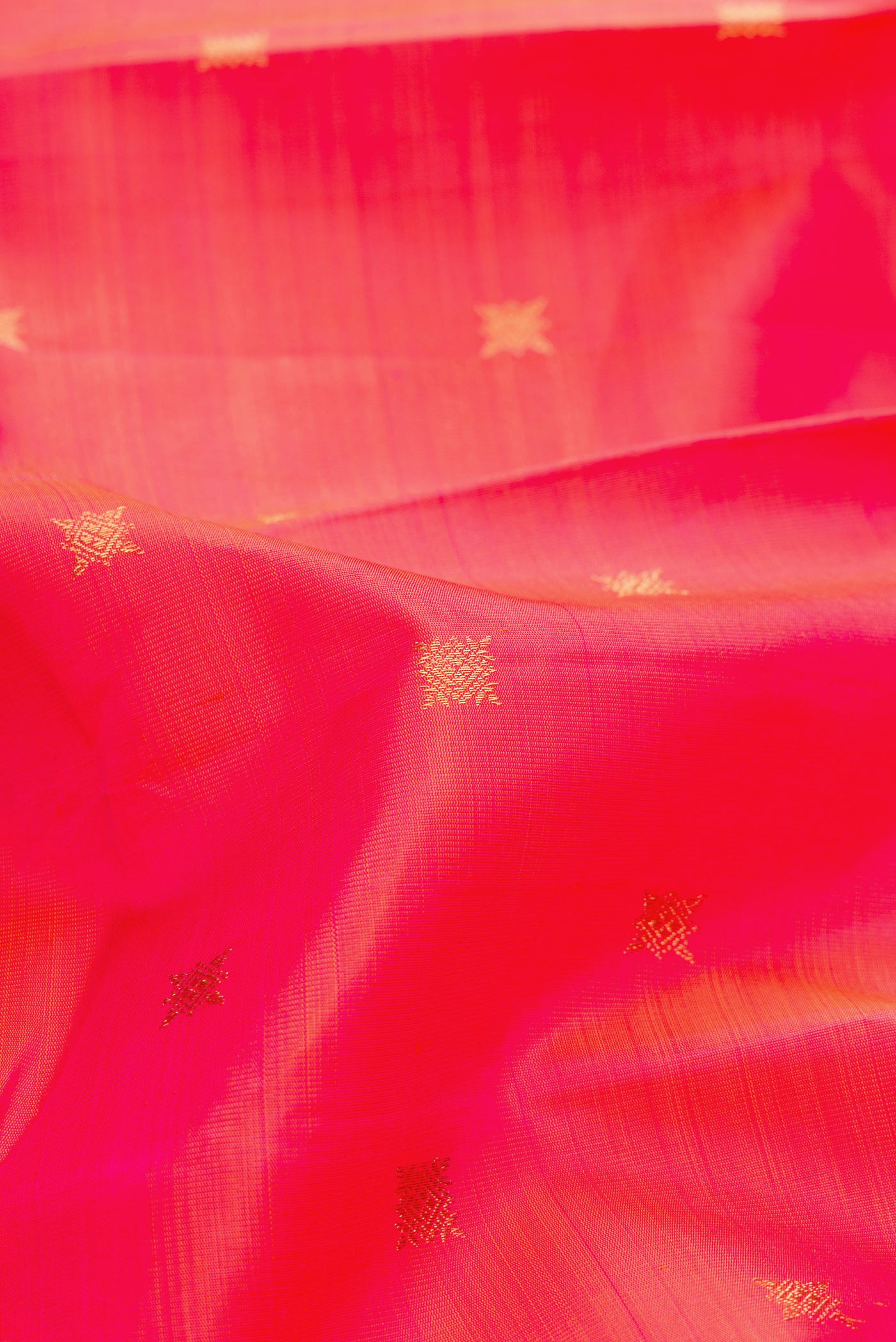 Close up of Pure Silk Pure Zari Coral Dual Tone Kanchipuram Saree with Zari Butta on the body and Zari Border.  displaying folds