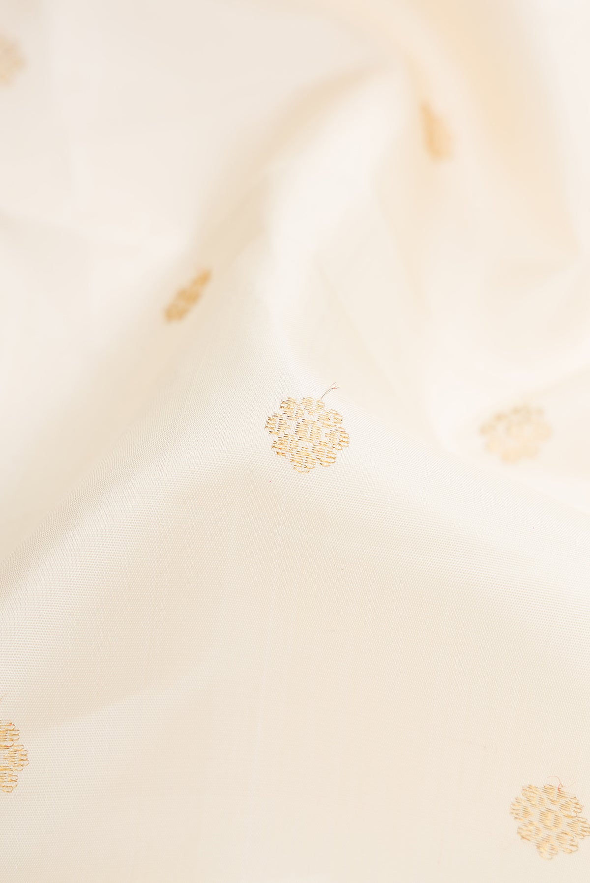 Close up of Pure Silk Pure Zari Off White Dual Tone Kanjivaram Saree with Zari Butta on the body and Zari Border.  displaying folds