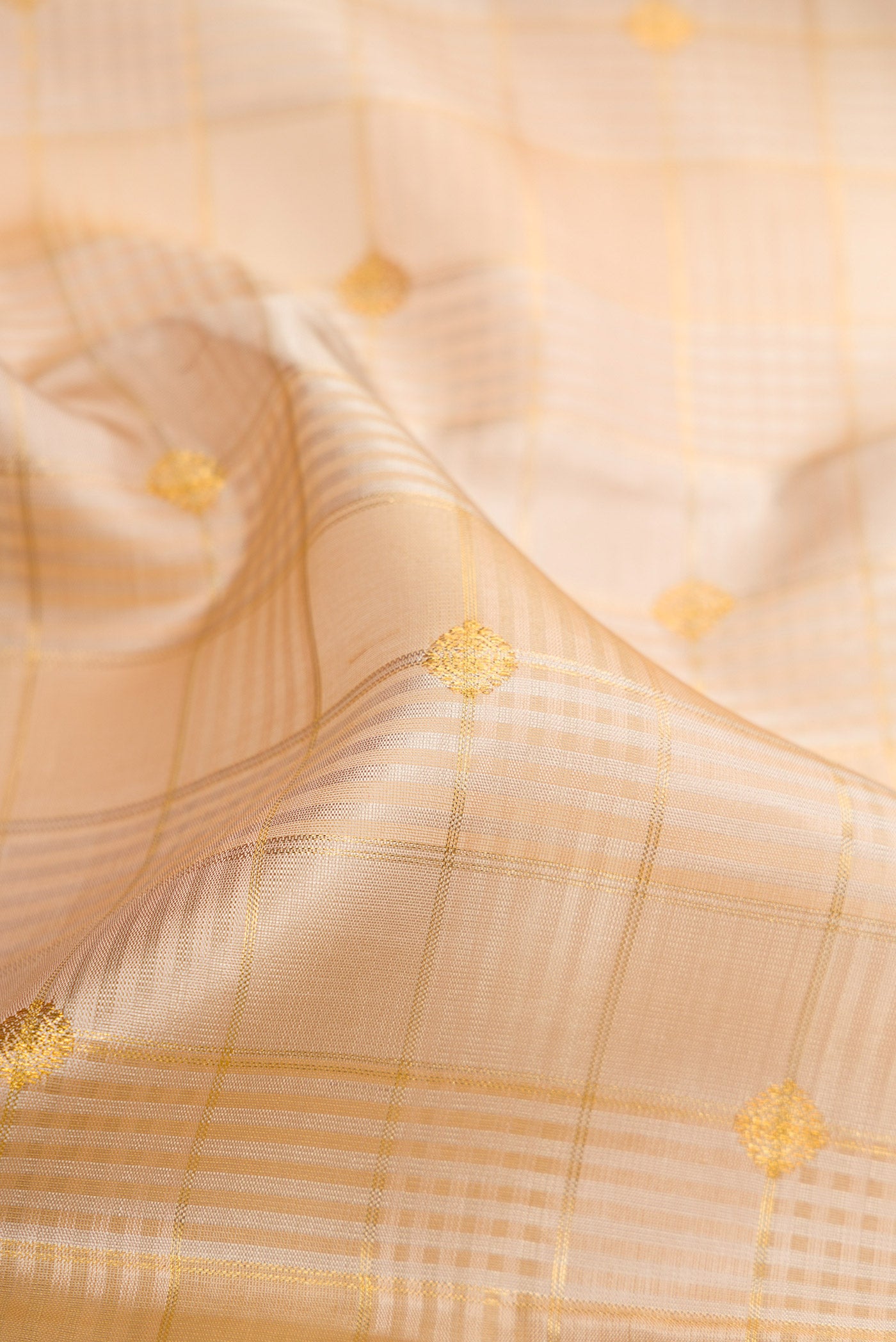 Close up of Pure Silk Pure Zari Beige Kanchipuram Saree with Checked design on the body and Zari Border.  displaying folds