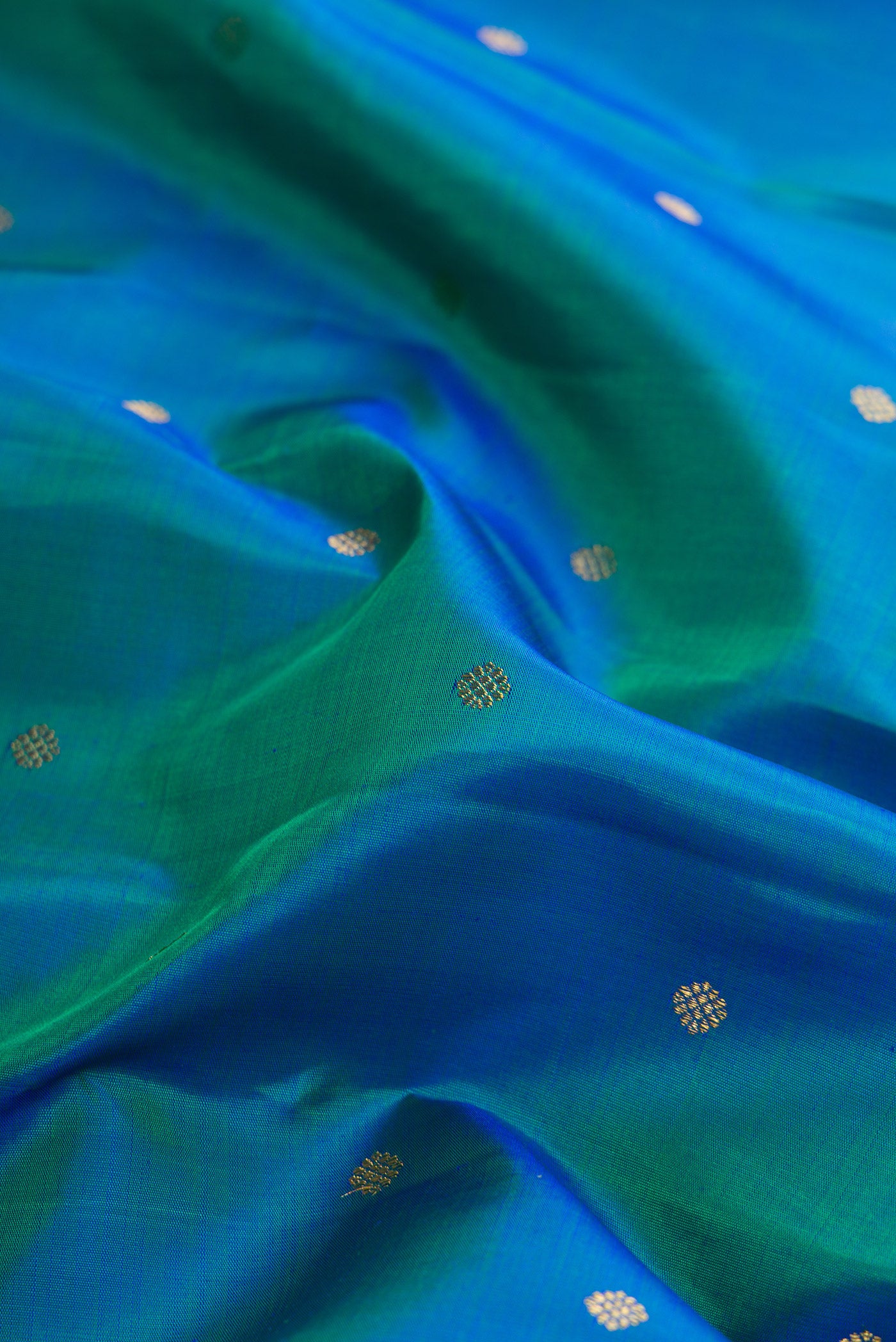 Close up of Pure Silk Pure Zari Peacock Blue Dual Tone Kanjivaram Saree with Zari Butta on the body and Zari Border.  displaying folds