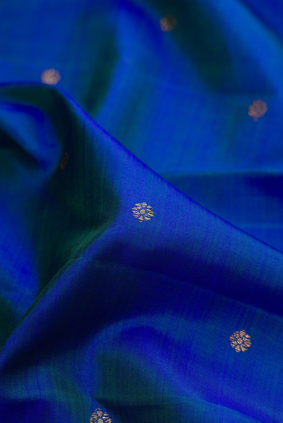 Close up of Pure Silk Pure Zari Peacock Blue Dual Tone Kanjivaram Saree with Zari Butta on the body and Zari Border.  displaying folds