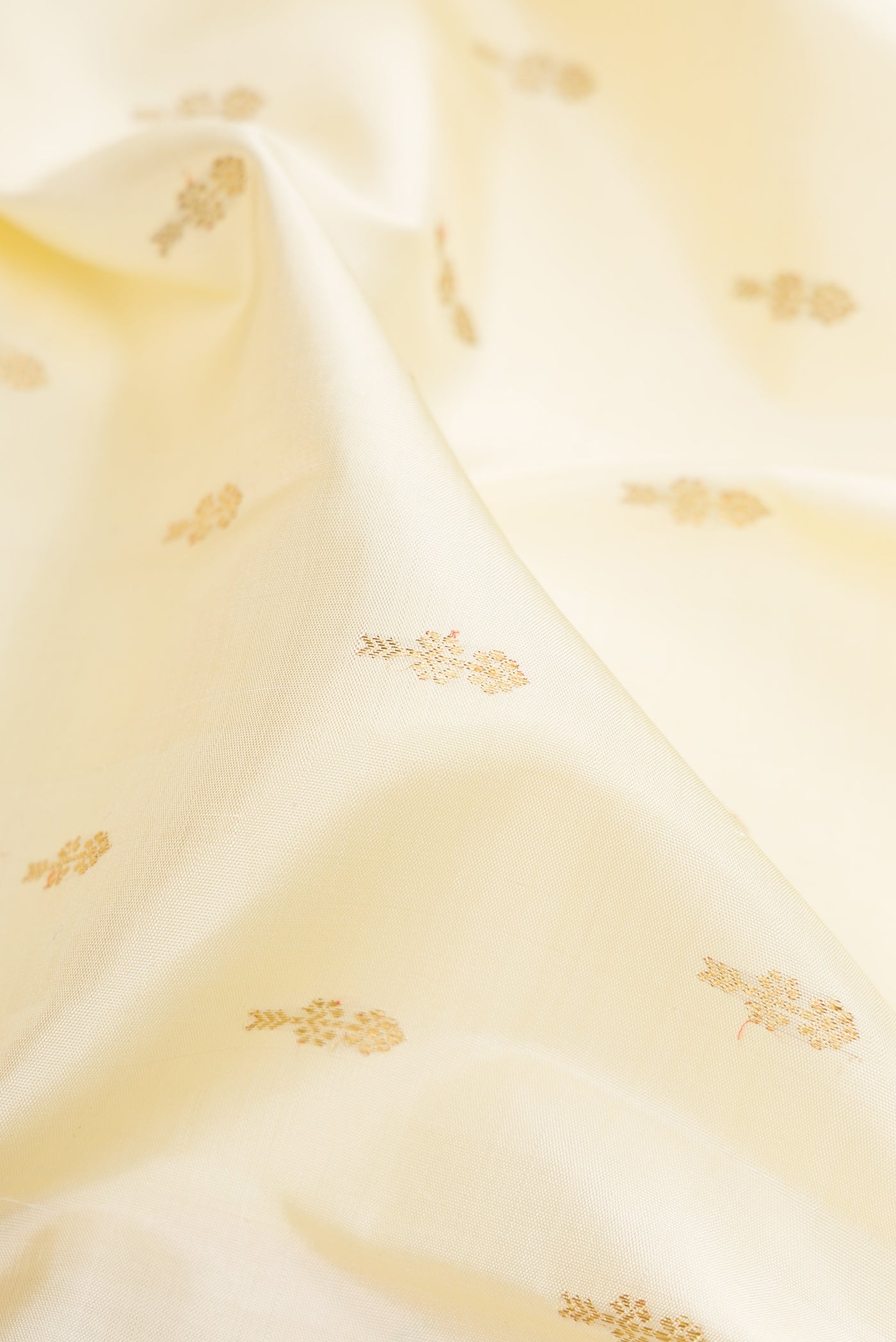 Close up of Pure Silk Pure Zari Off White Kanjivaram Saree with Zari Butta on the body and Zari Border.  displaying folds