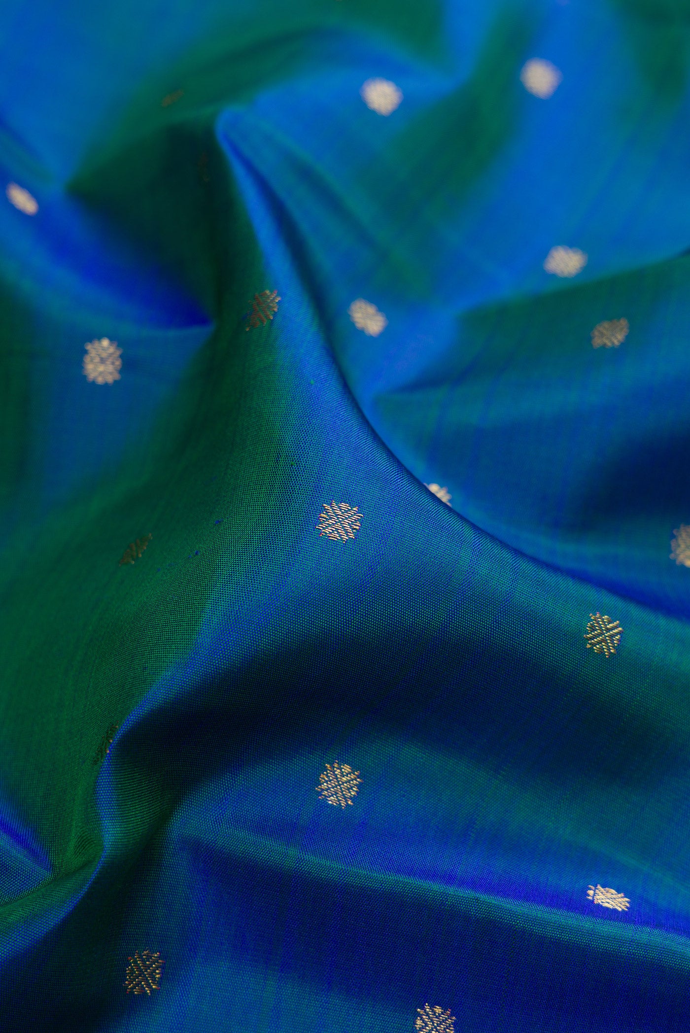 Close up of Pure Silk Pure Zari Peacock Blue Dual Tone Kanjivaram Saree with Zari Butta on the body and Zari Border.  displaying folds