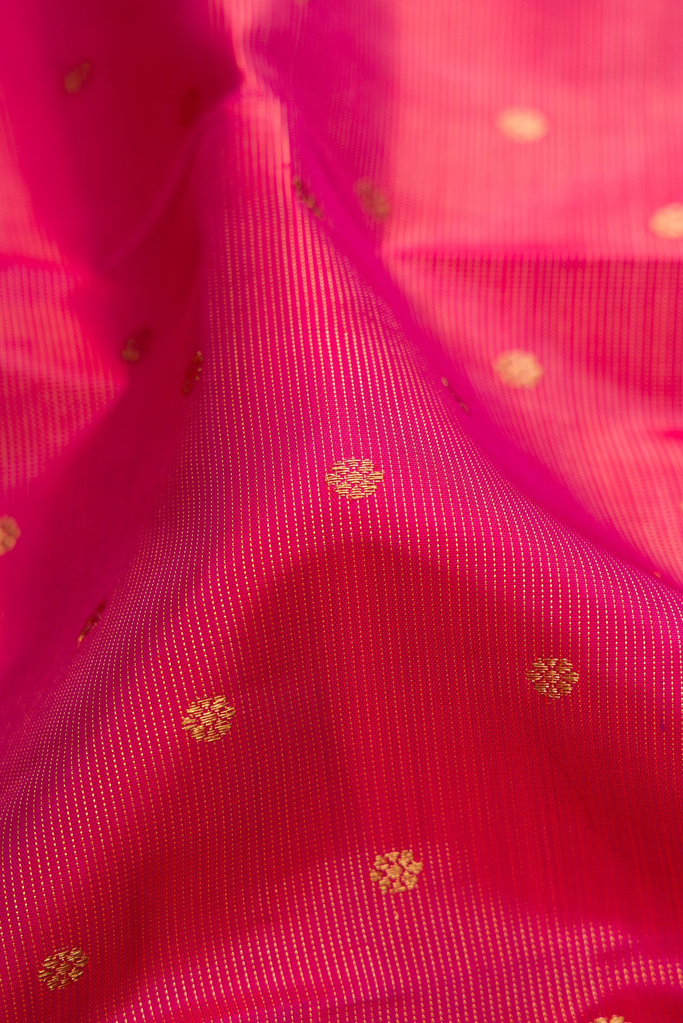 Close up of Pure Silk Pure Zari Rani Pink Kanjivaram Saree with Zari Butta on the body and Zari Border.  displaying folds