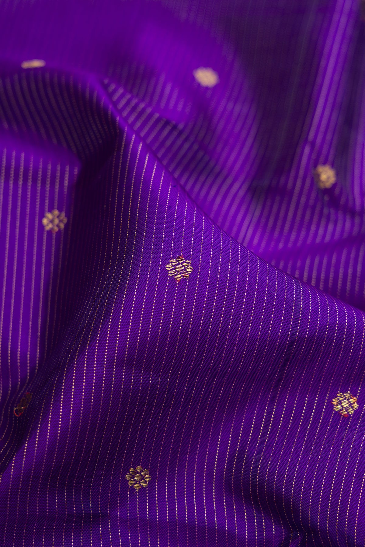 Close up of Pure Silk Pure Zari Violet Dual Tone Kanjivaram Saree with Stripes on the body and Zari Border.  displaying folds
