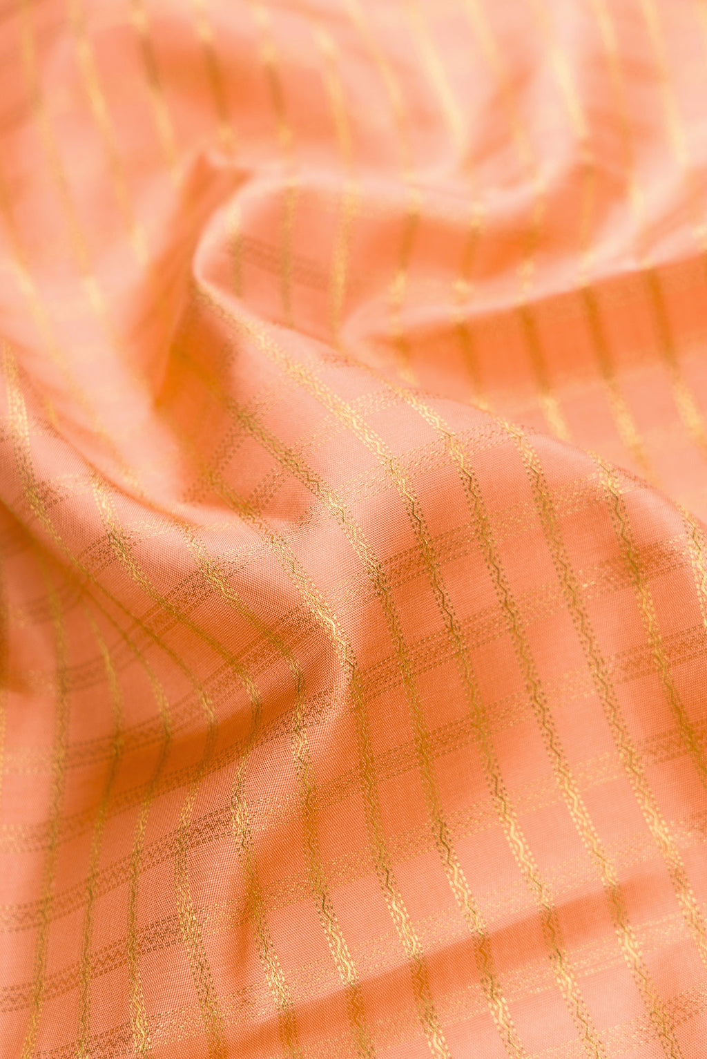 Close up of Pure Silk Pure Zari Golden Peach Dual Tone Kanjivaram Saree with Checked design on the body and Zari Border.  displaying folds