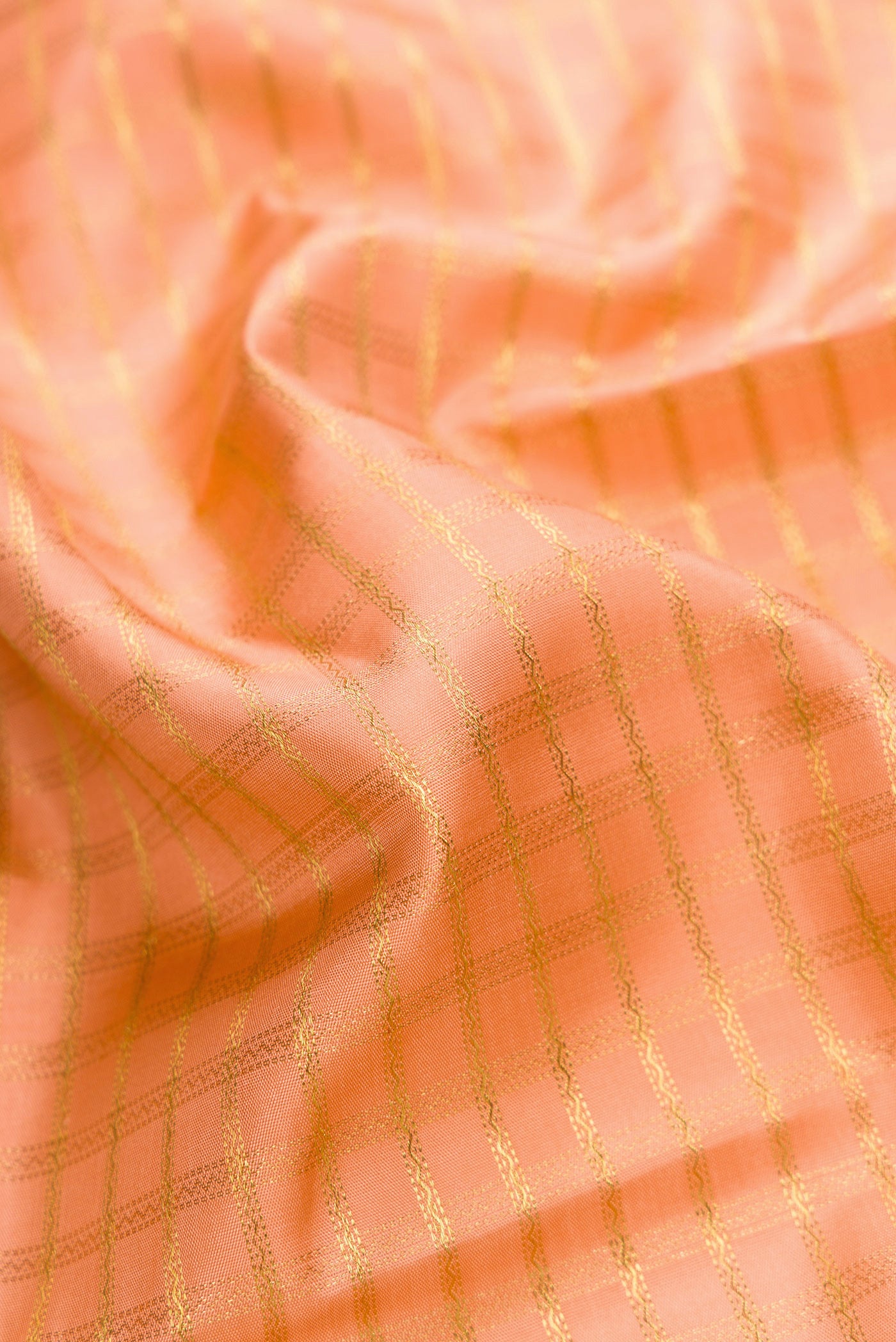 Close up of Pure Silk Pure Zari Golden Peach Dual Tone Kanjivaram Saree with Checked design on the body and Zari Border.  displaying folds