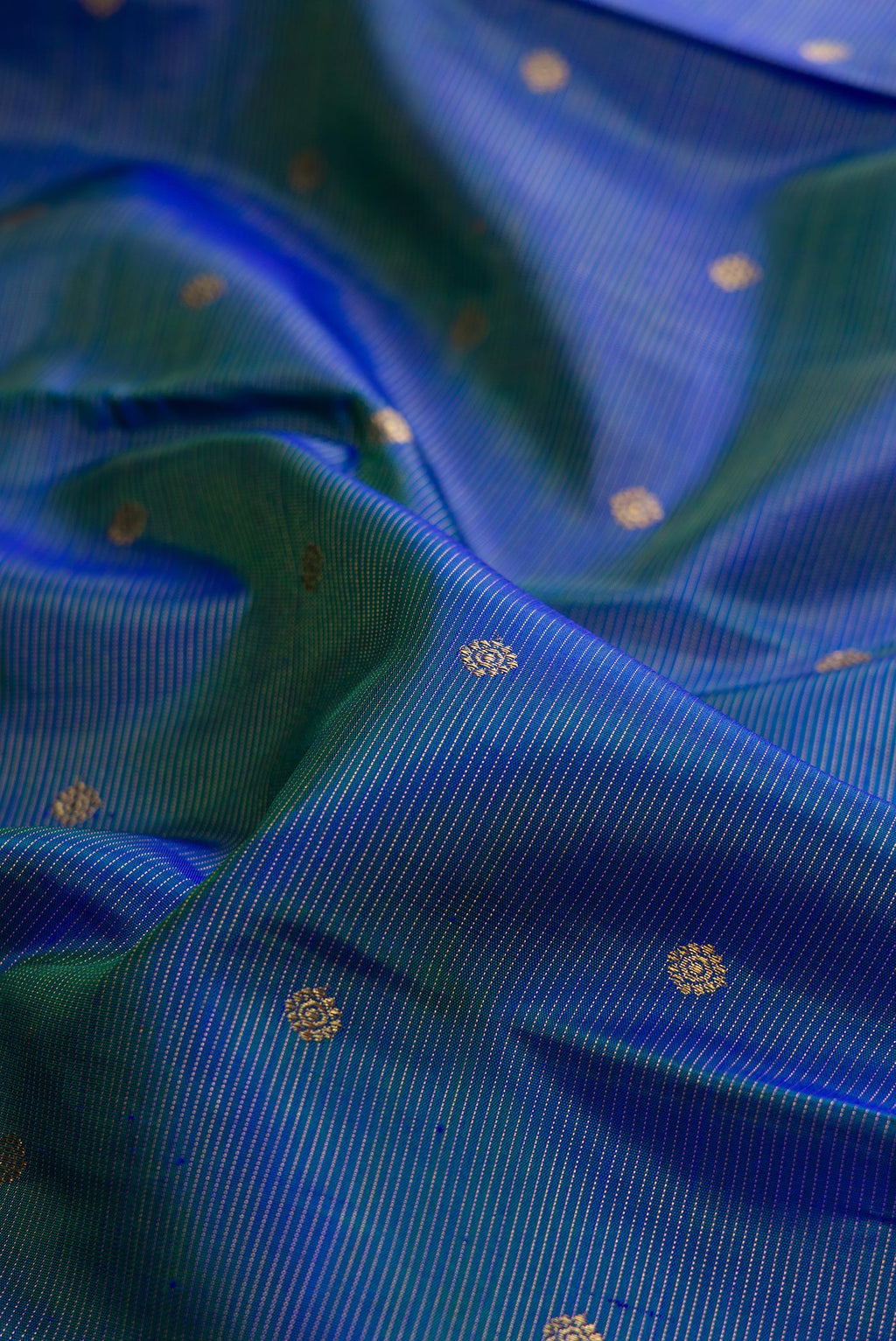 Close up of Pure Silk Pure Zari Peacock Blue Dual Tone Kanjivaram Saree with Zari Butta on the body and Zari Border.  displaying folds