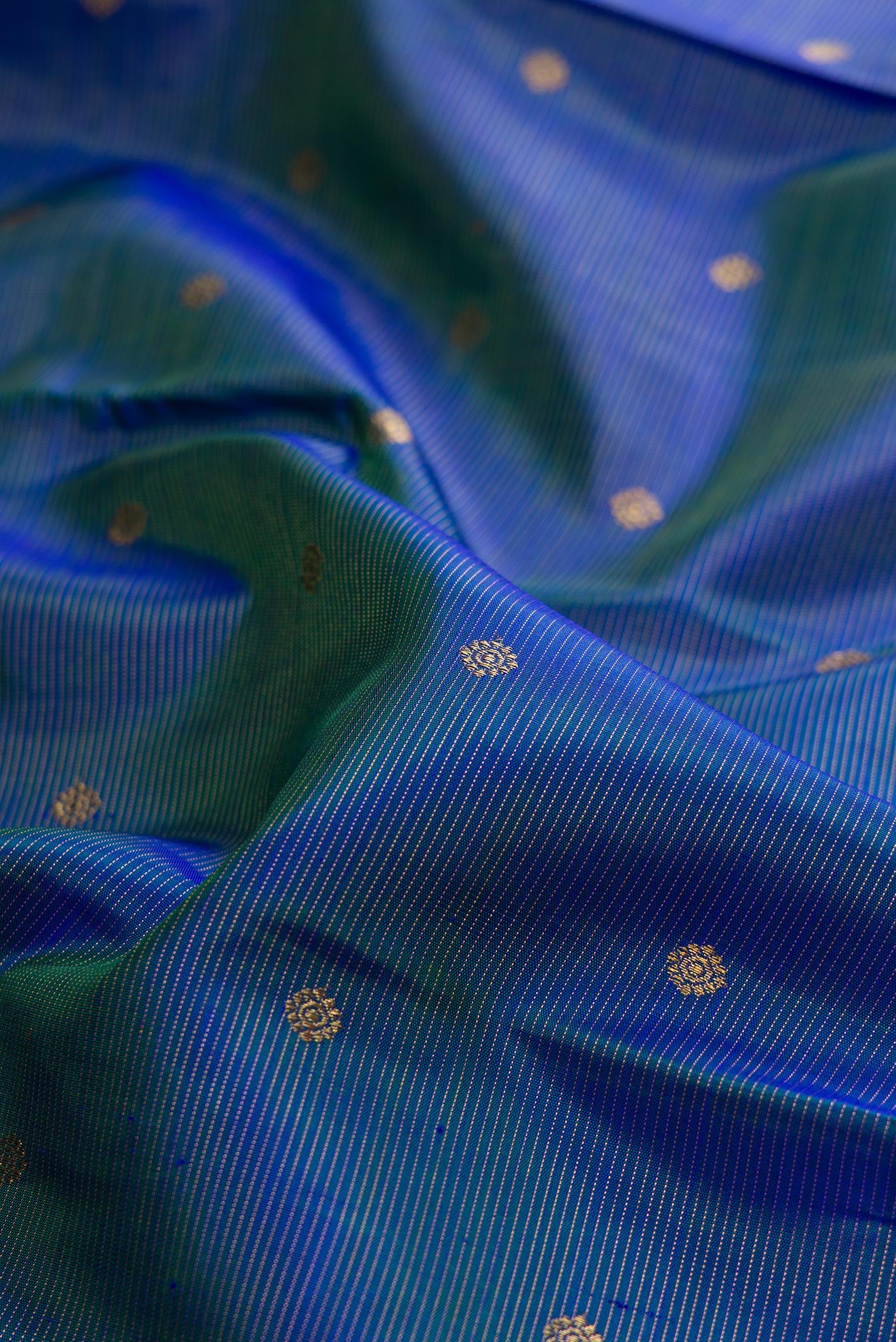 Close up of Pure Silk Pure Zari Peacock Blue Dual Tone Kanjivaram Saree with Zari Butta on the body and Zari Border.  displaying folds