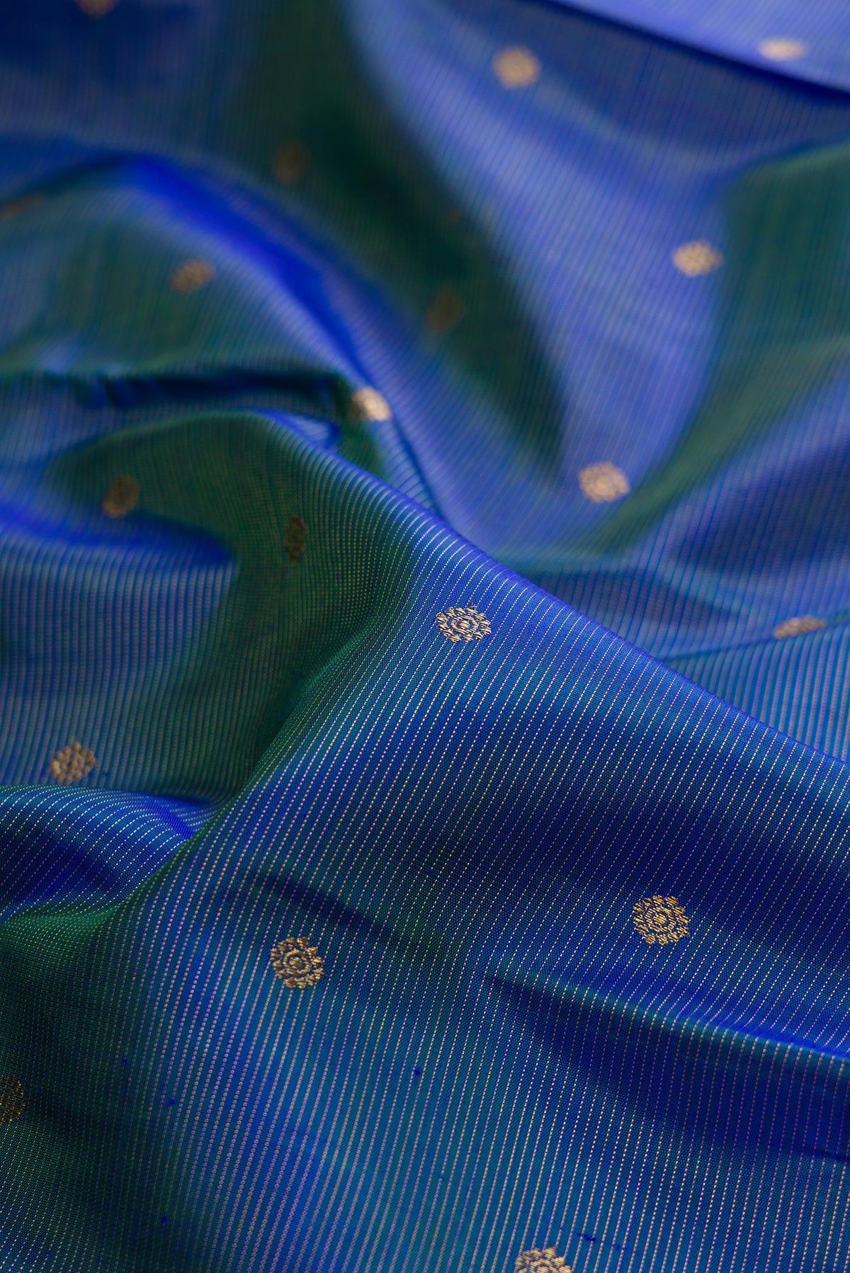 Close up of Pure Silk Pure Zari Peacock Blue Dual Tone Kanjivaram Saree with Zari Butta on the body and Zari Border.  displaying folds