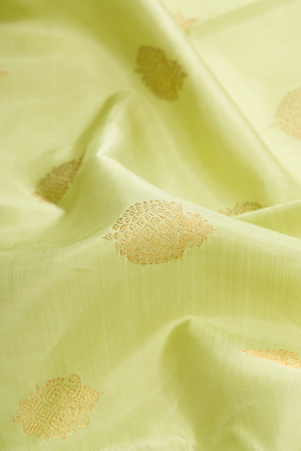 Close up of Pure Silk Pure Zari Pista Green Dual Tone Kanchipuram Saree with Zari Butta on the body and Without Border.  displaying folds