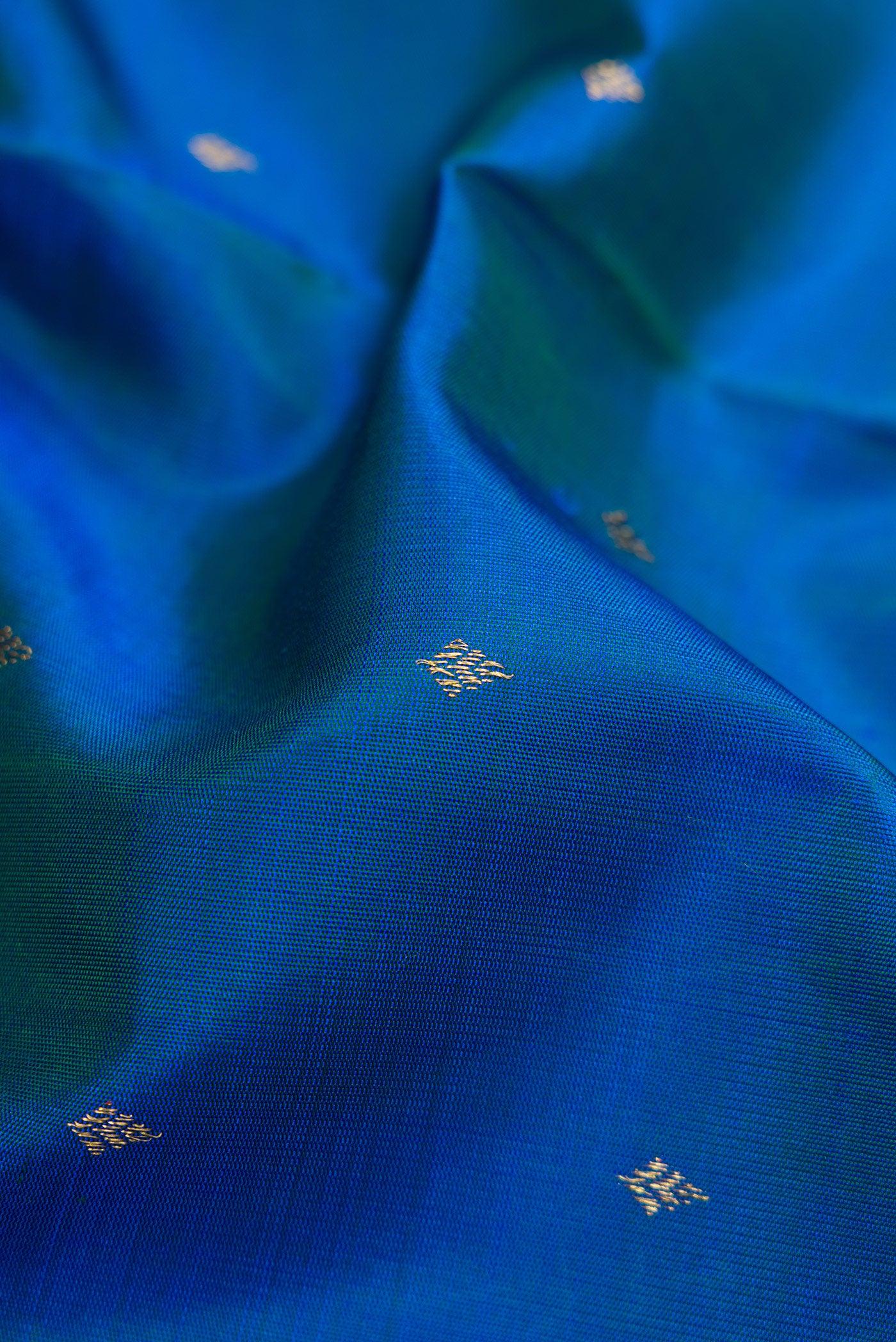 Close up of Pure Silk Pure Zari Peacock Blue Dual Tone Kanjivaram Saree with Zari Butta on the body and Zari Border.  displaying folds