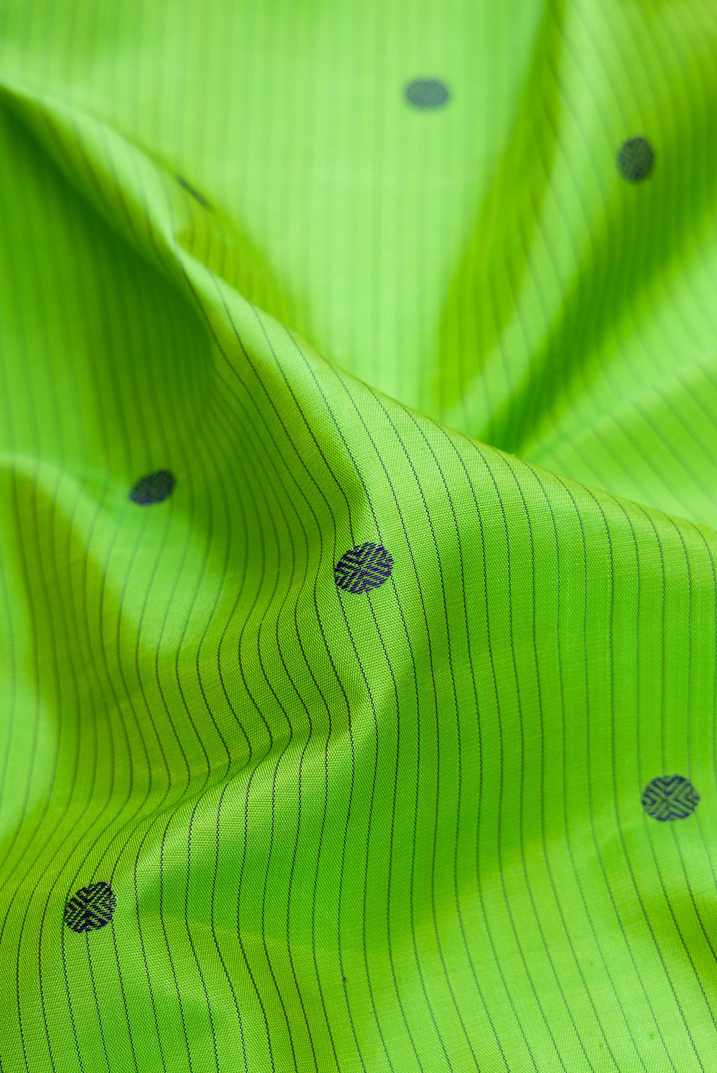 Close up of Pure Silk Pure Zari Parrot Green Dual Tone Kanjivaram Saree with Stripes on the body and Zari And Thread Border.  displaying folds