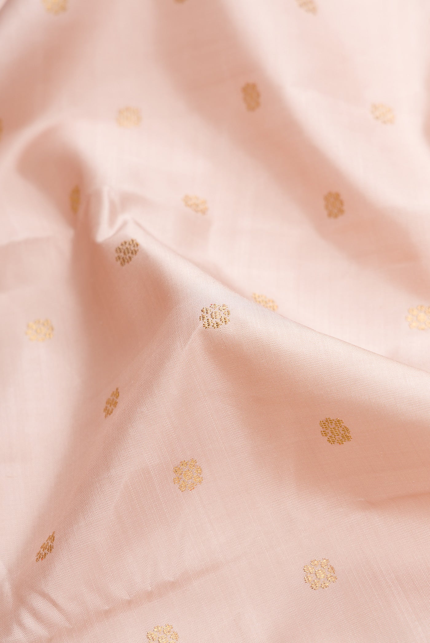 Close up of Pure Silk Pure Zari Rose Gold Dual Tone Kanjivaram Saree with Zari Butta on the body and Zari Border.  displaying folds