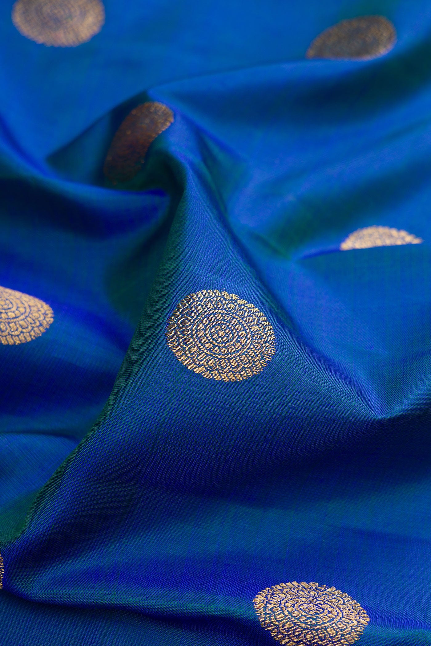 Close up of Pure Silk Pure Zari Peacock Blue Kanjivaram Saree with Zari Butta on the body and Zari Border.  displaying folds