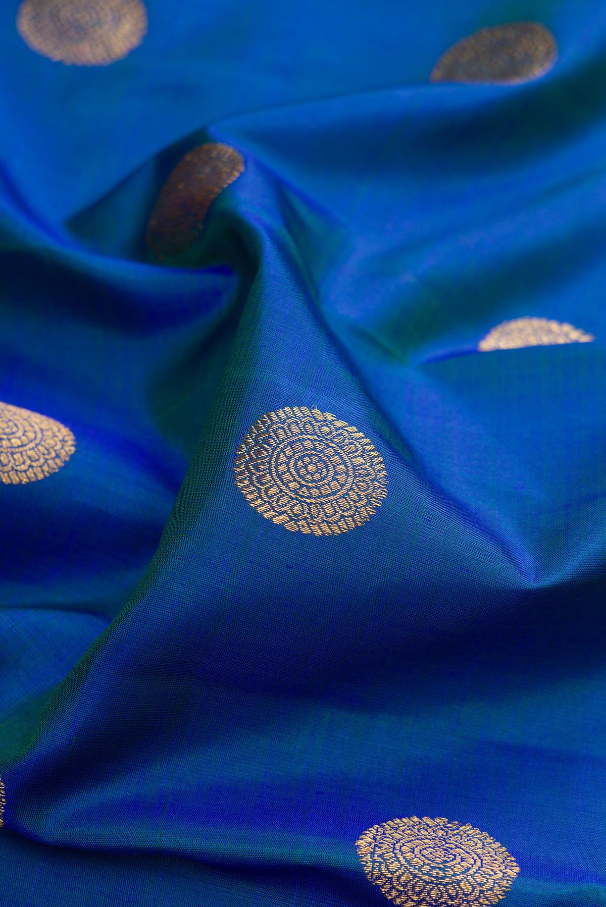 Close up of Pure Silk Pure Zari Peacock Blue Kanjivaram Saree with Zari Butta on the body and Zari Border.  displaying folds