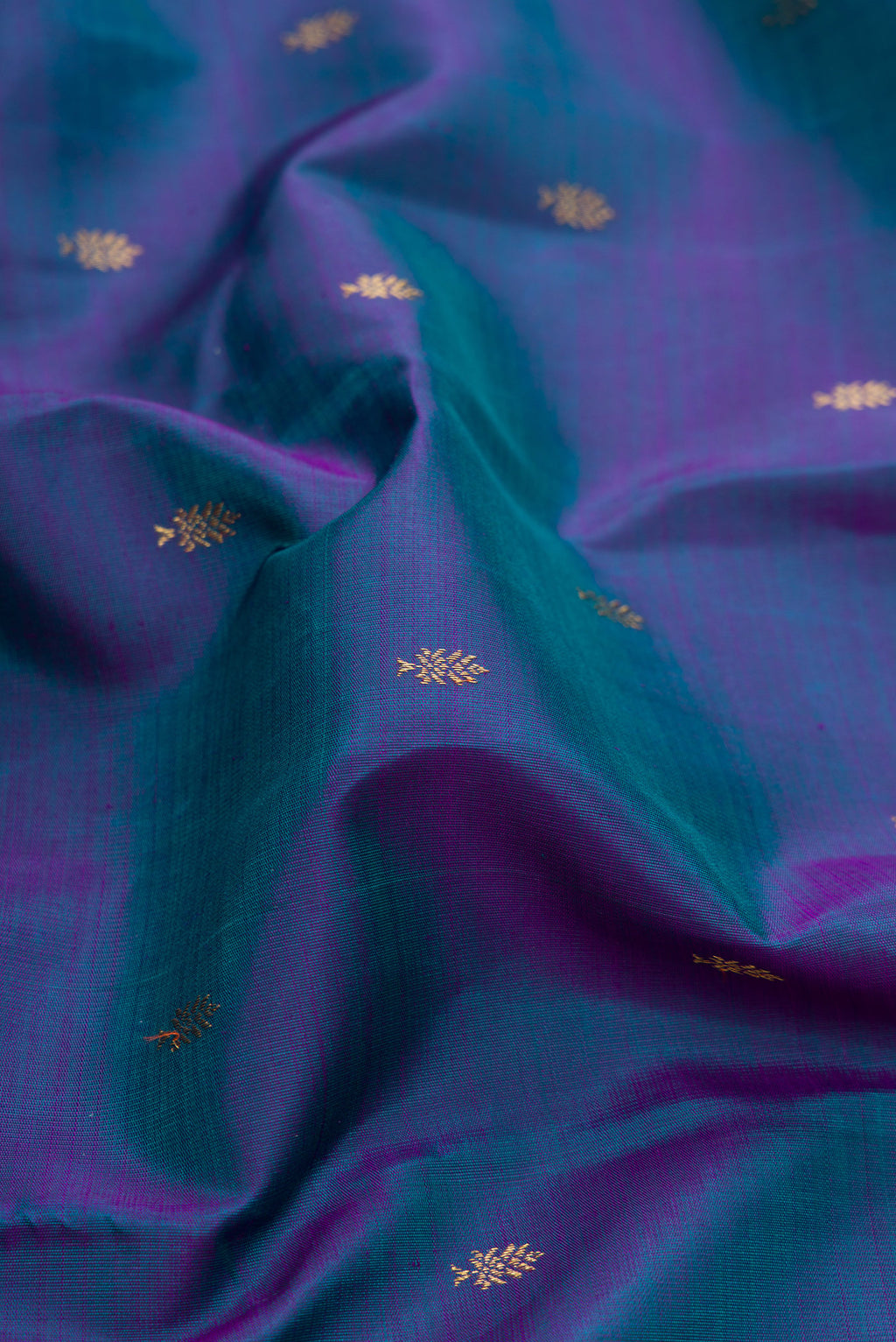 Close up of Pure Silk Pure Zari Peacock Blue Dual Tone Kanjivaram Saree with Zari Butta on the body and Zari Border.  displaying folds