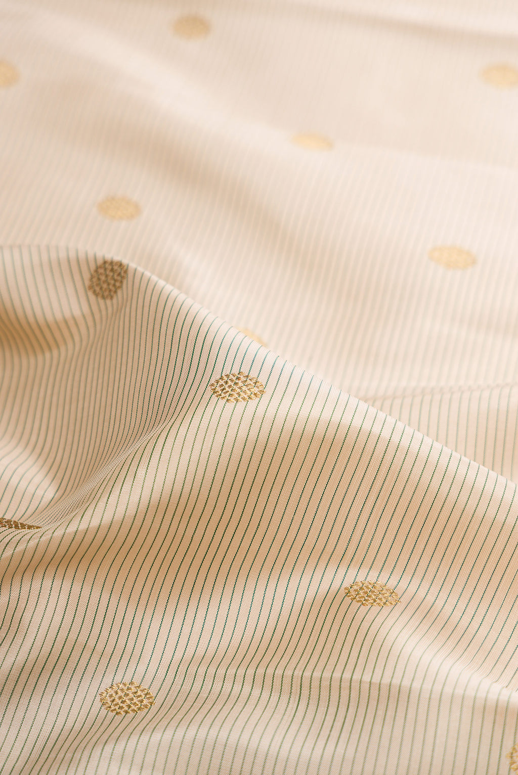 Close up of Pure Silk Pure Zari Cream Kanjivaram Saree with Zari Butta on the body and Zari Border.  displaying folds