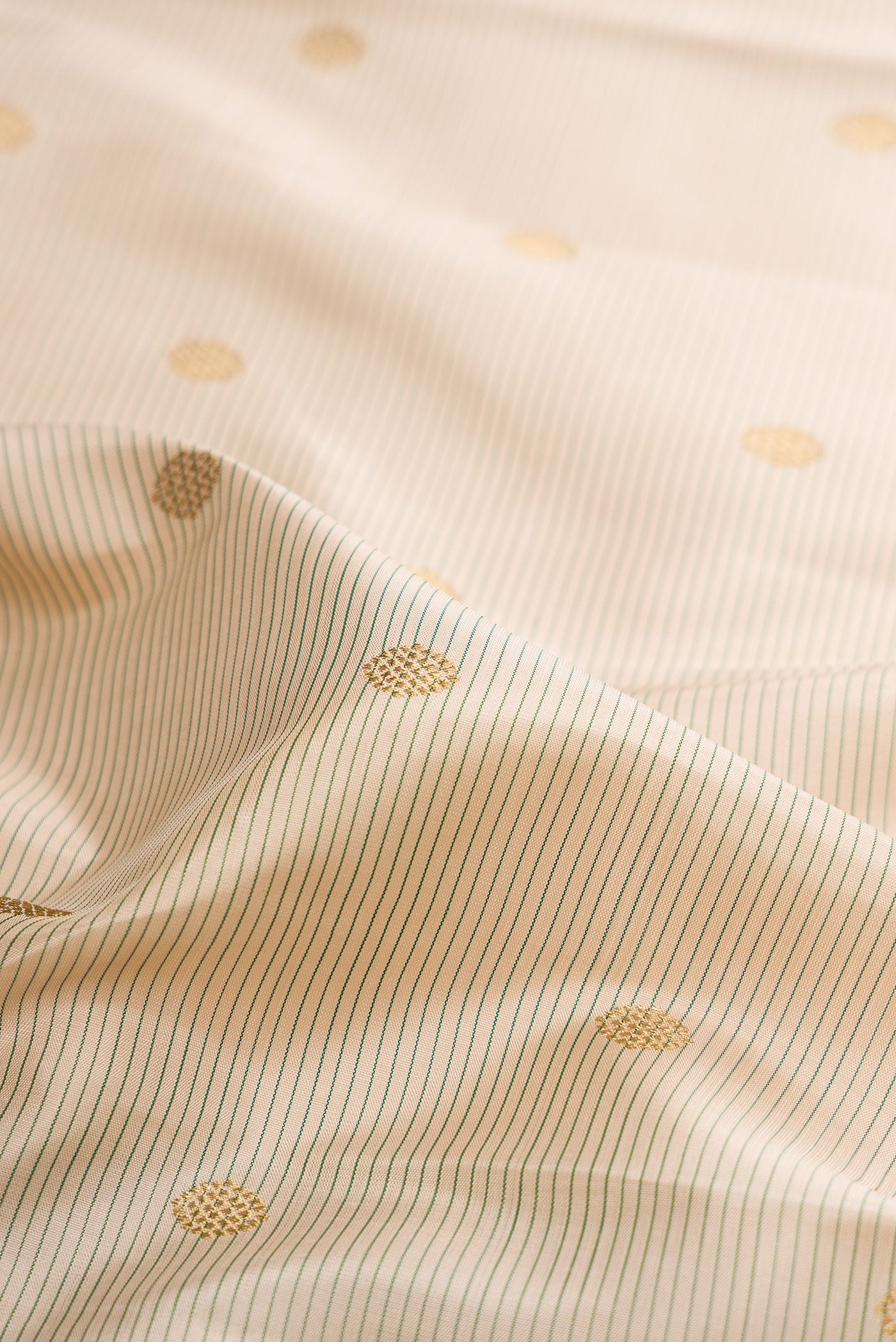 Close up of Pure Silk Pure Zari Cream Kanjivaram Saree with Zari Butta on the body and Zari Border.  displaying folds