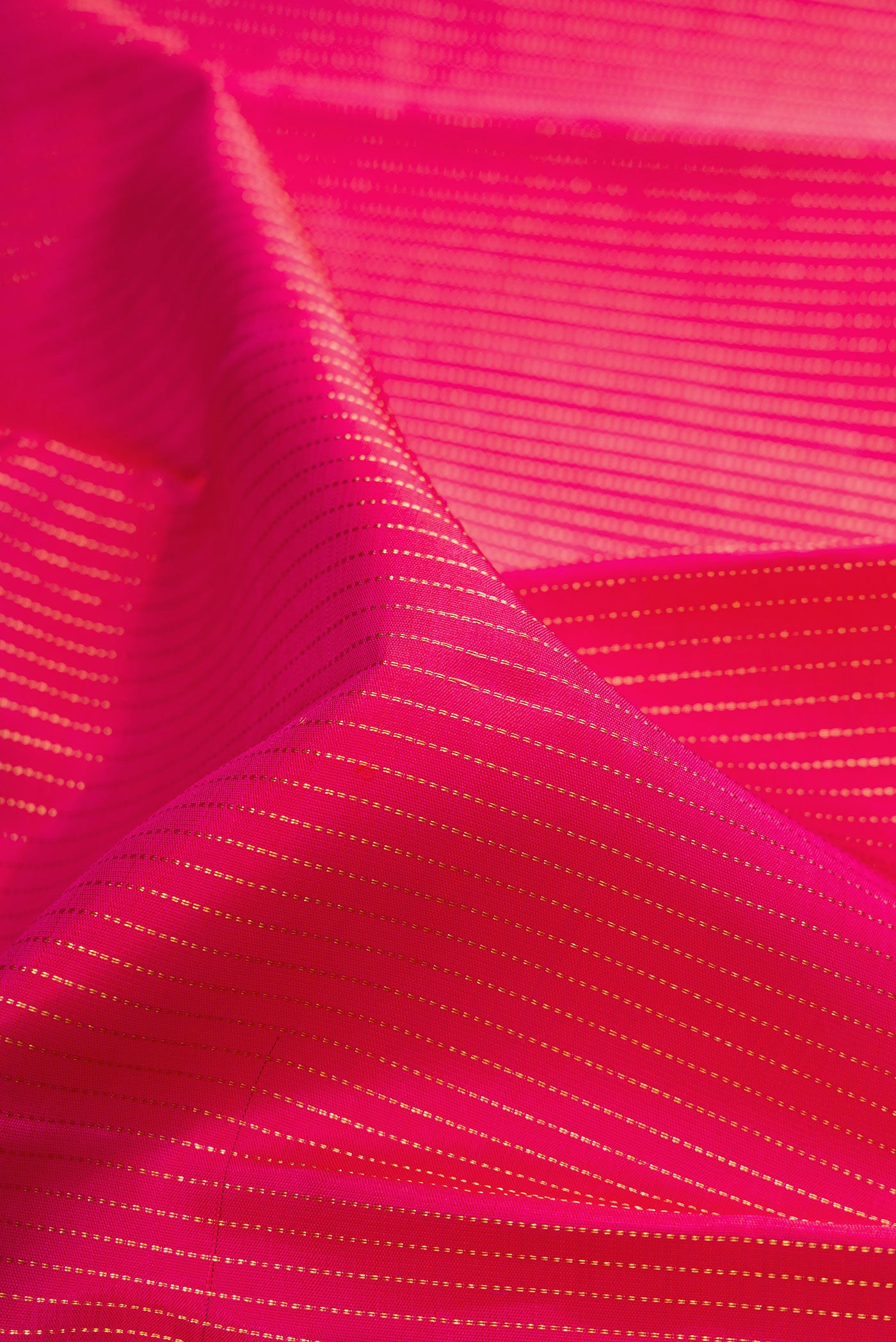 Close up of Rani Pink Kanchipuram Silk Saree with Stripes on the body and Fancy Border.  displaying folds