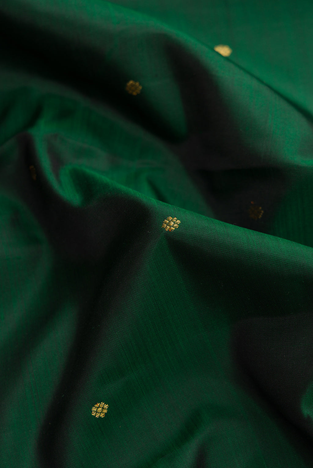 Close up of Green Dual Tone Kanjivaram Silk Saree with Zari Butta on the body and Zari Border.  displaying folds