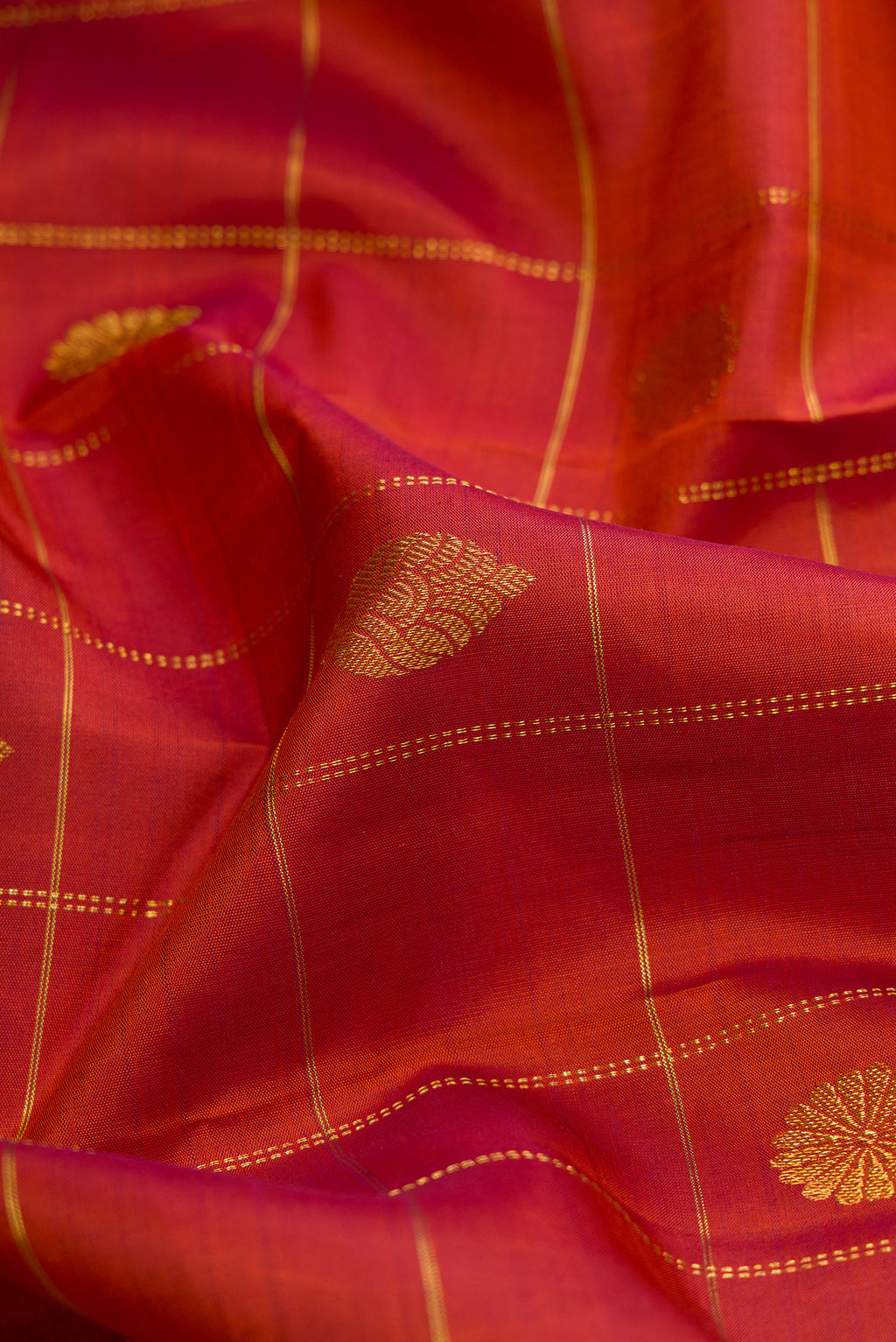 Close up of Brick Orange Dual Tone Kanjivaram Silk Saree with Checked design on the body and Zari Border.  displaying folds