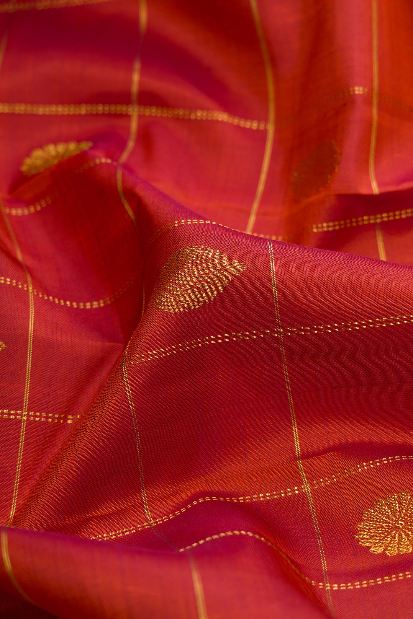 Close up of Brick Orange Dual Tone Kanjivaram Silk Saree with Checked design on the body and Zari Border.  displaying folds