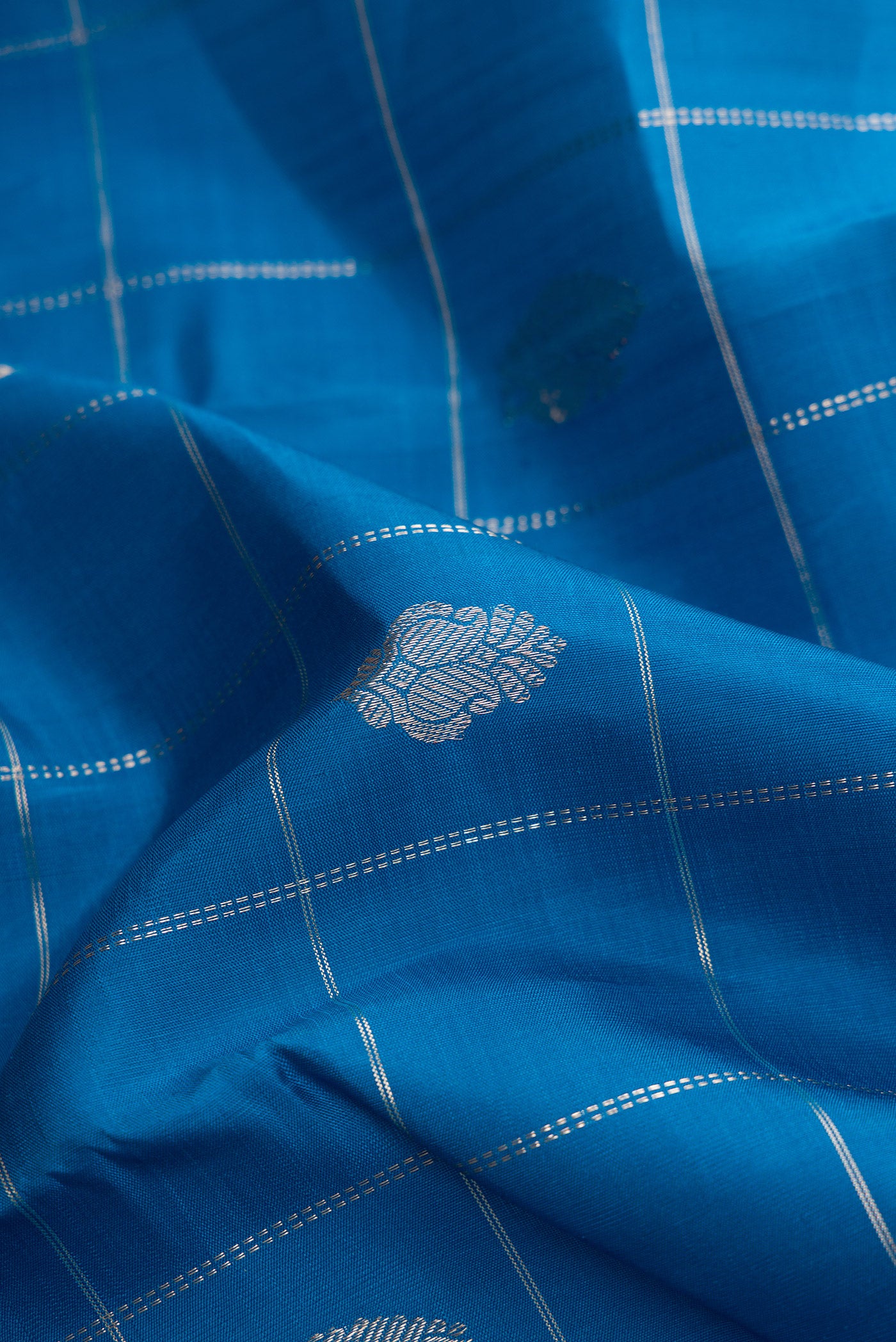 Close up of Peacock Blue Dual Tone Kanjivaram Silk Saree with Checked design on the body and Zari Border.  displaying folds