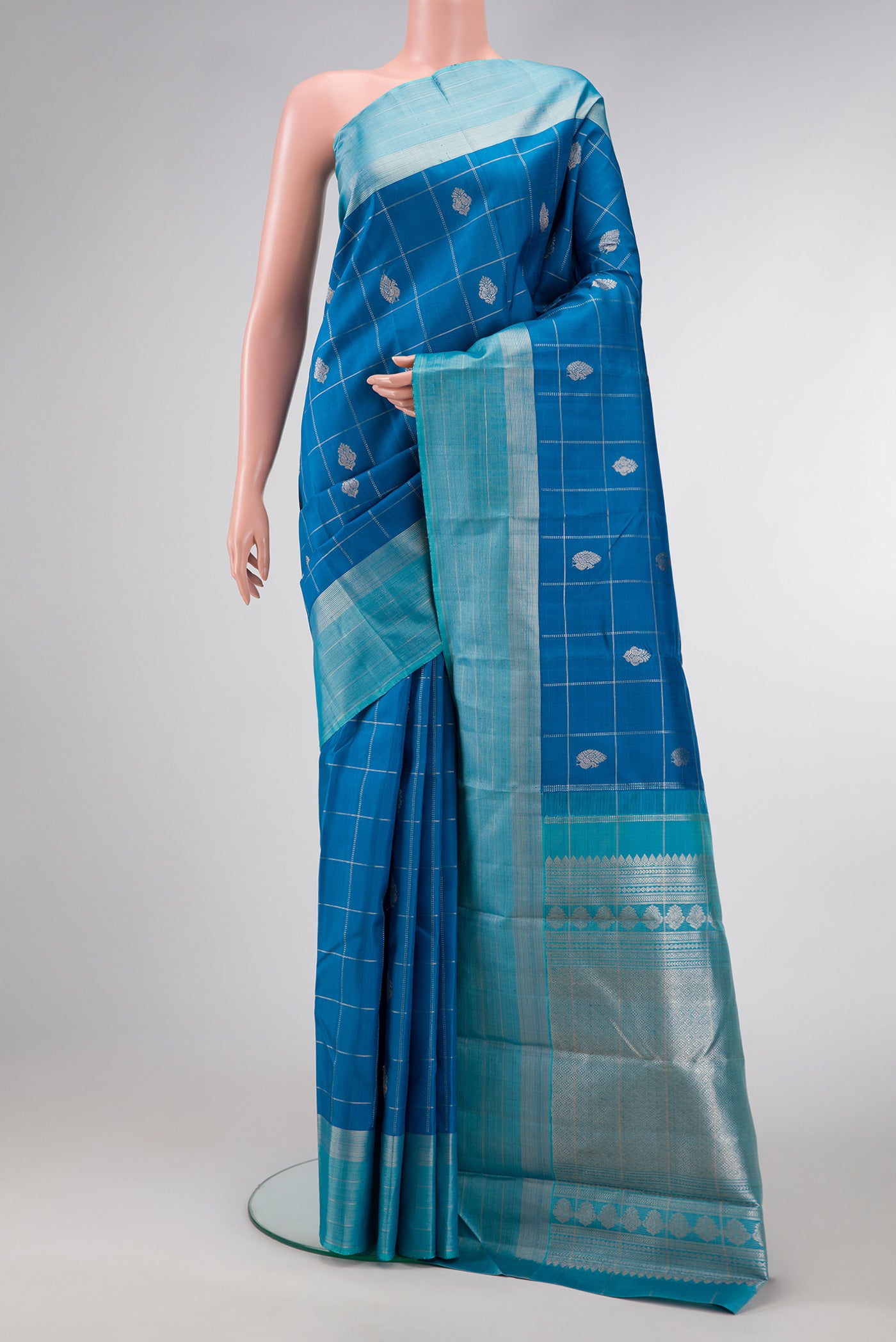 Peacock Blue Dual Tone Kanjivaram Silk Saree with Checked design on the body and Zari Border.  displayed on a mannequin