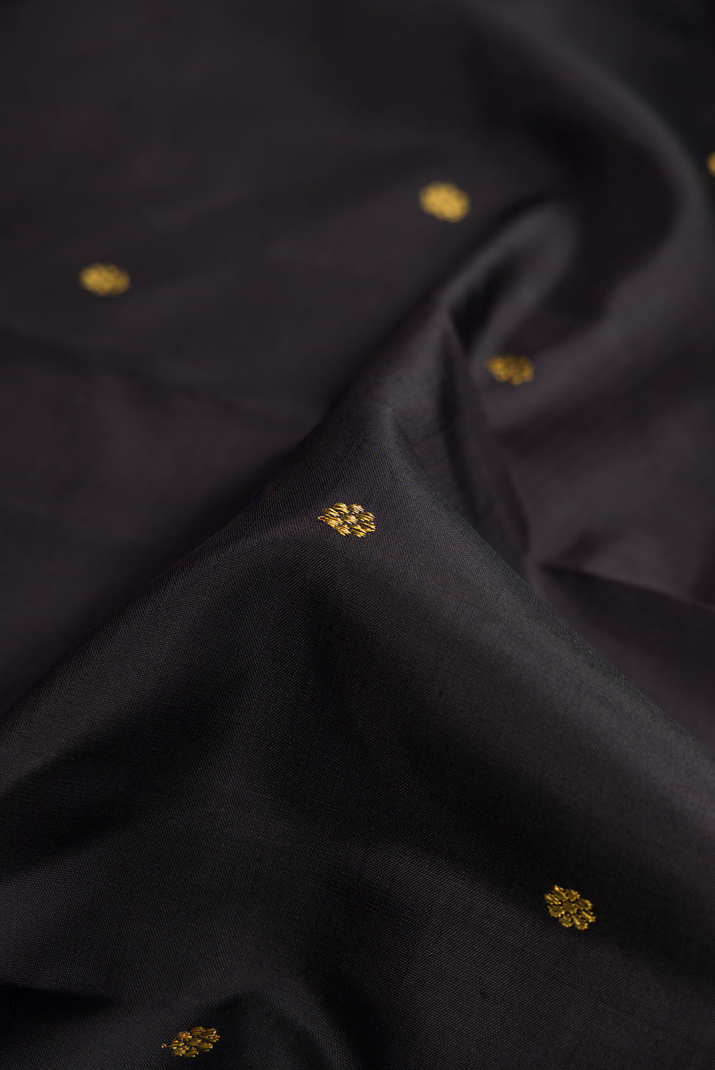 Close up of Pure Silk Pure Zari Black Dual Tone Kanchipuram Saree with Zari Butta on the body and Zari Border.  displaying folds