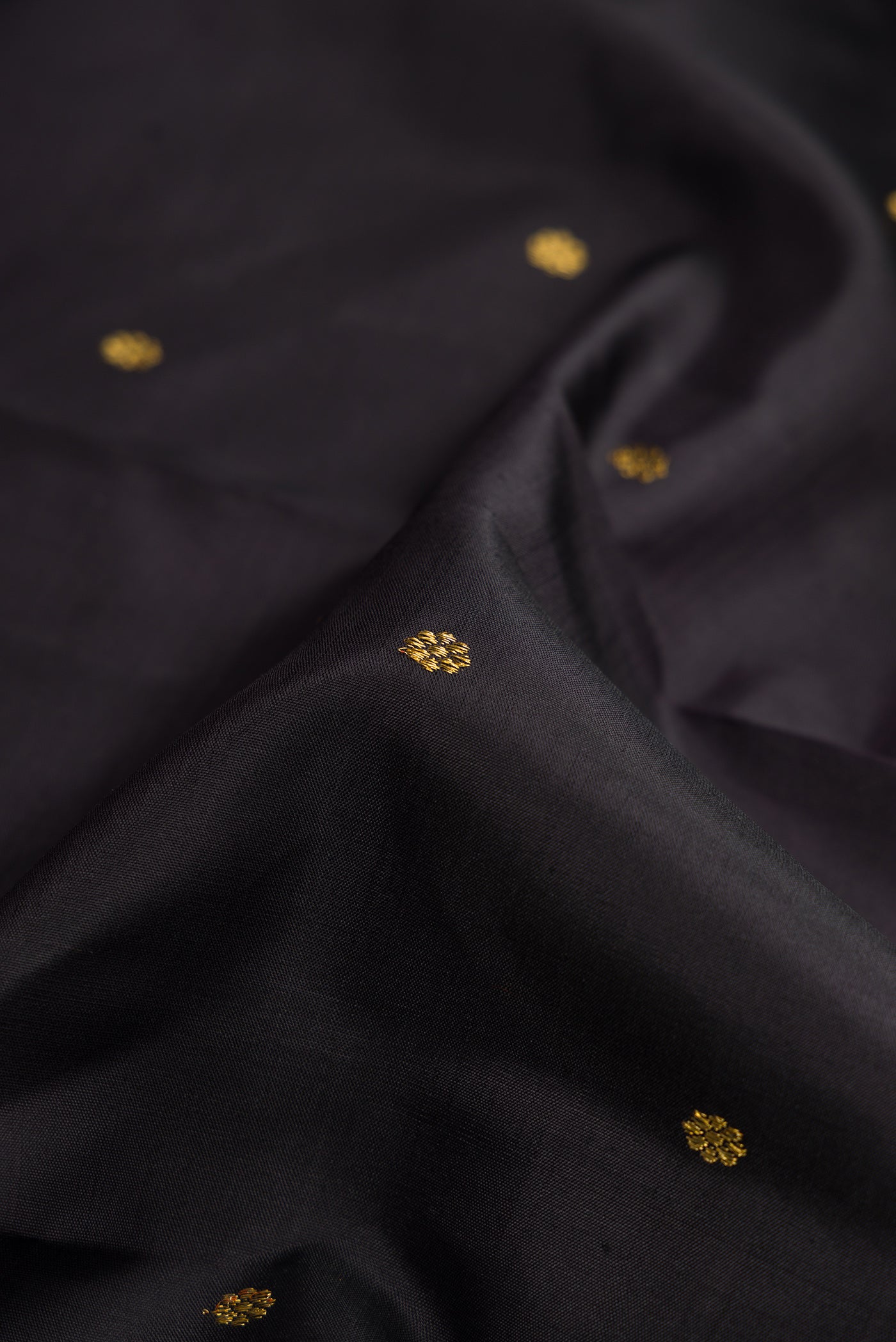 Close up of Pure Silk Pure Zari Black Dual Tone Kanchipuram Saree with Zari Butta on the body and Zari Border.  displaying folds