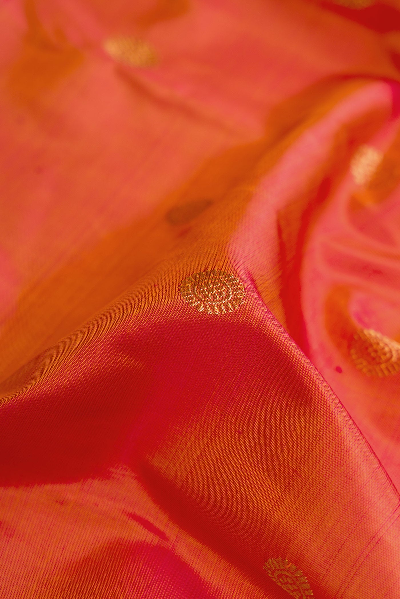Close up of Pure Silk Pure Zari Brick Orange Dual Tone Kanjivaram Saree with Zari Butta on the body and Zari Border.  displaying folds