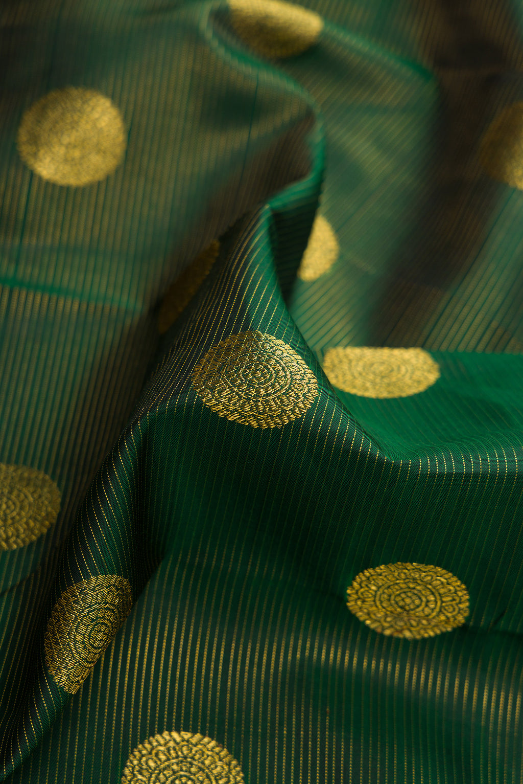 Close up of Green Dual Tone Kanchipuram Silk Saree with Zari Butta on the body and Zari Border.  displaying folds