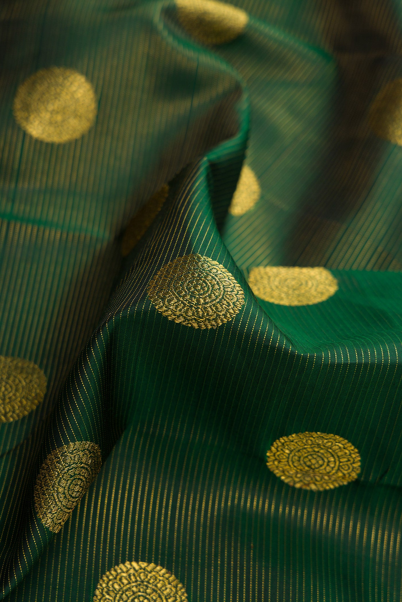 Close up of Green Dual Tone Kanchipuram Silk Saree with Zari Butta on the body and Zari Border.  displaying folds