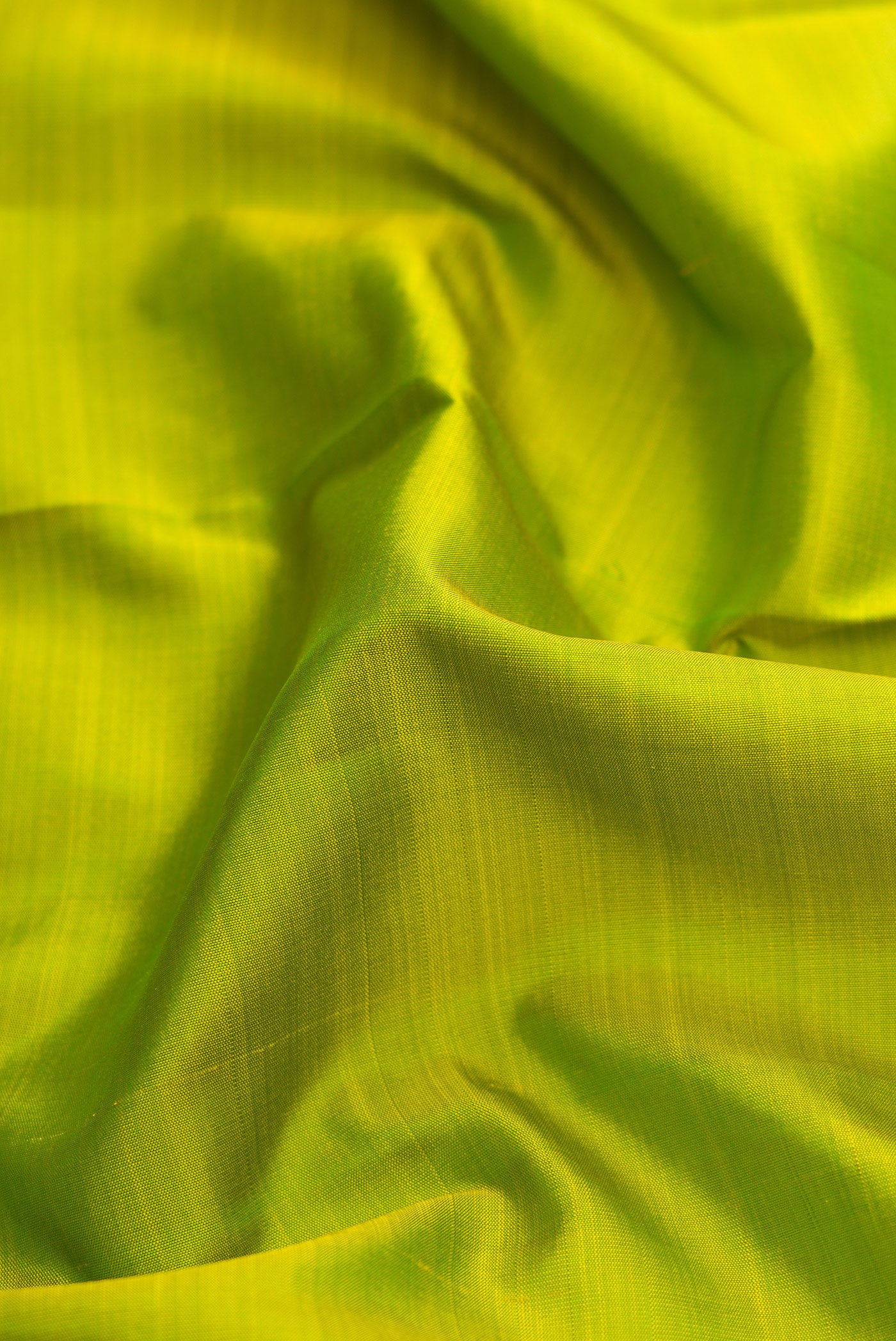 Close up of Pure Silk Pure Zari Parrot Green Dual Tone Kanjivaram Saree with Plain Body and Temple Border.  displaying folds