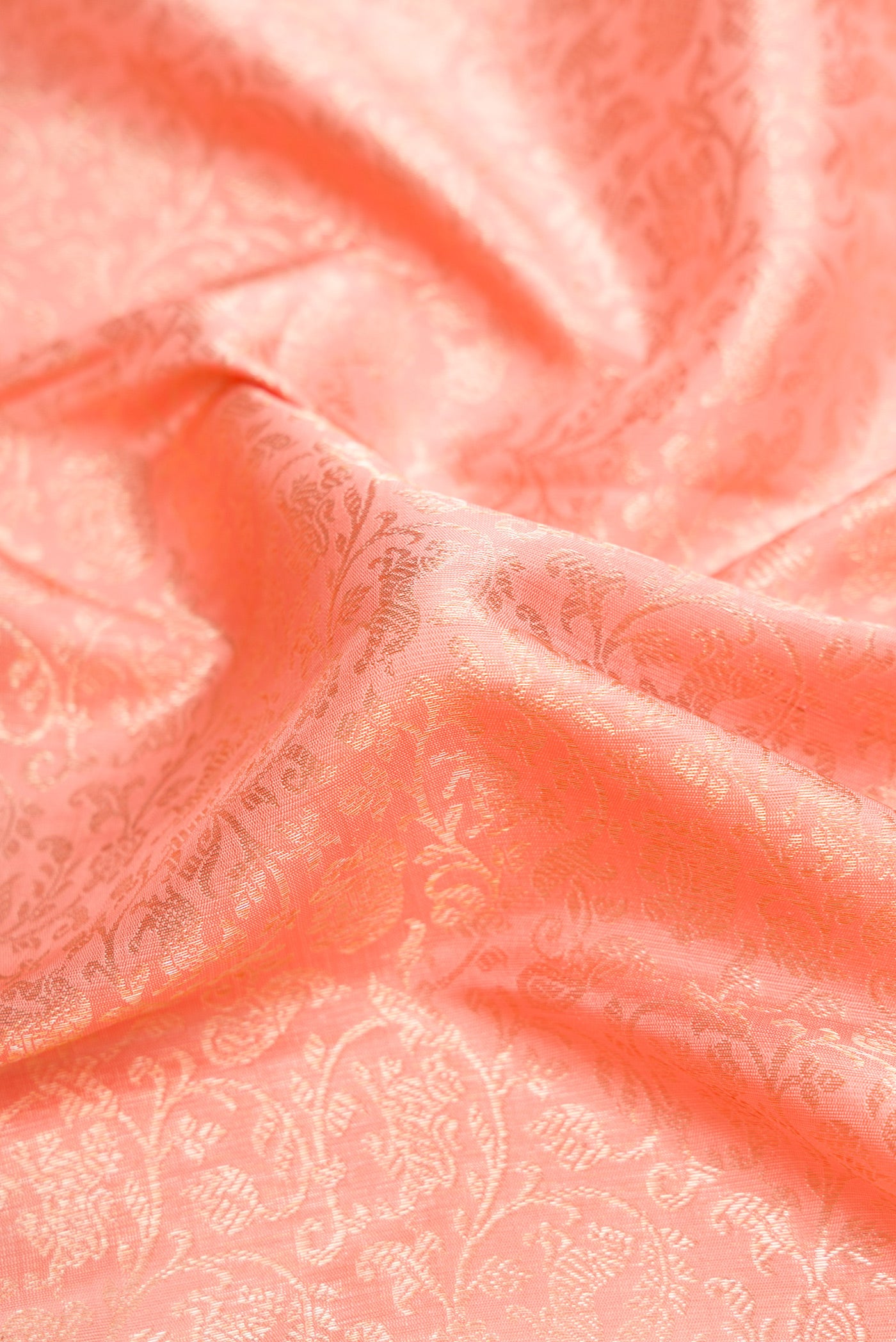 Close up of Peach Dual Tone Kanchipuram Silk Saree with Zari Brocade on the body and Zari Border.  displaying folds