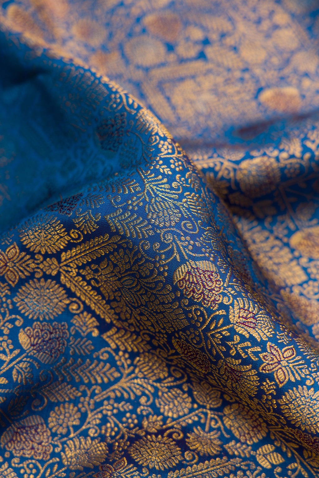 Close up of Peacock Blue Dual Tone Kanchipuram Silk Saree with Zari Brocade on the body and Zari Border.  displaying folds