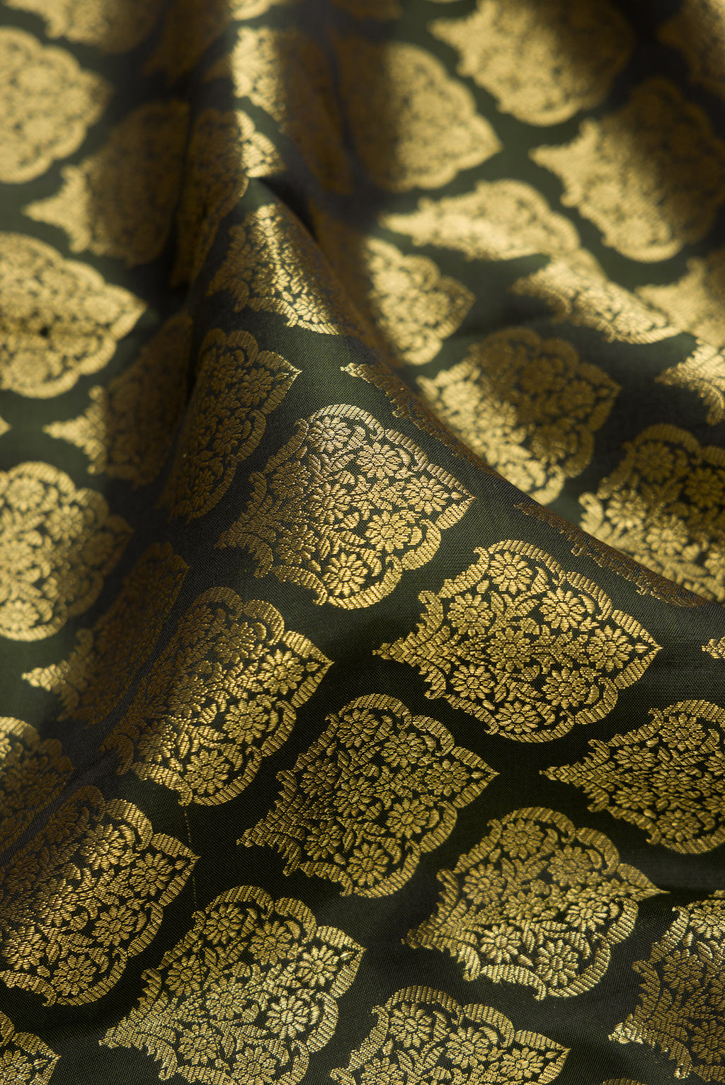 Close up of Bottle Green Kanchipuram Silk Saree with Zari Brocade on the body and Zari Border.  displaying folds